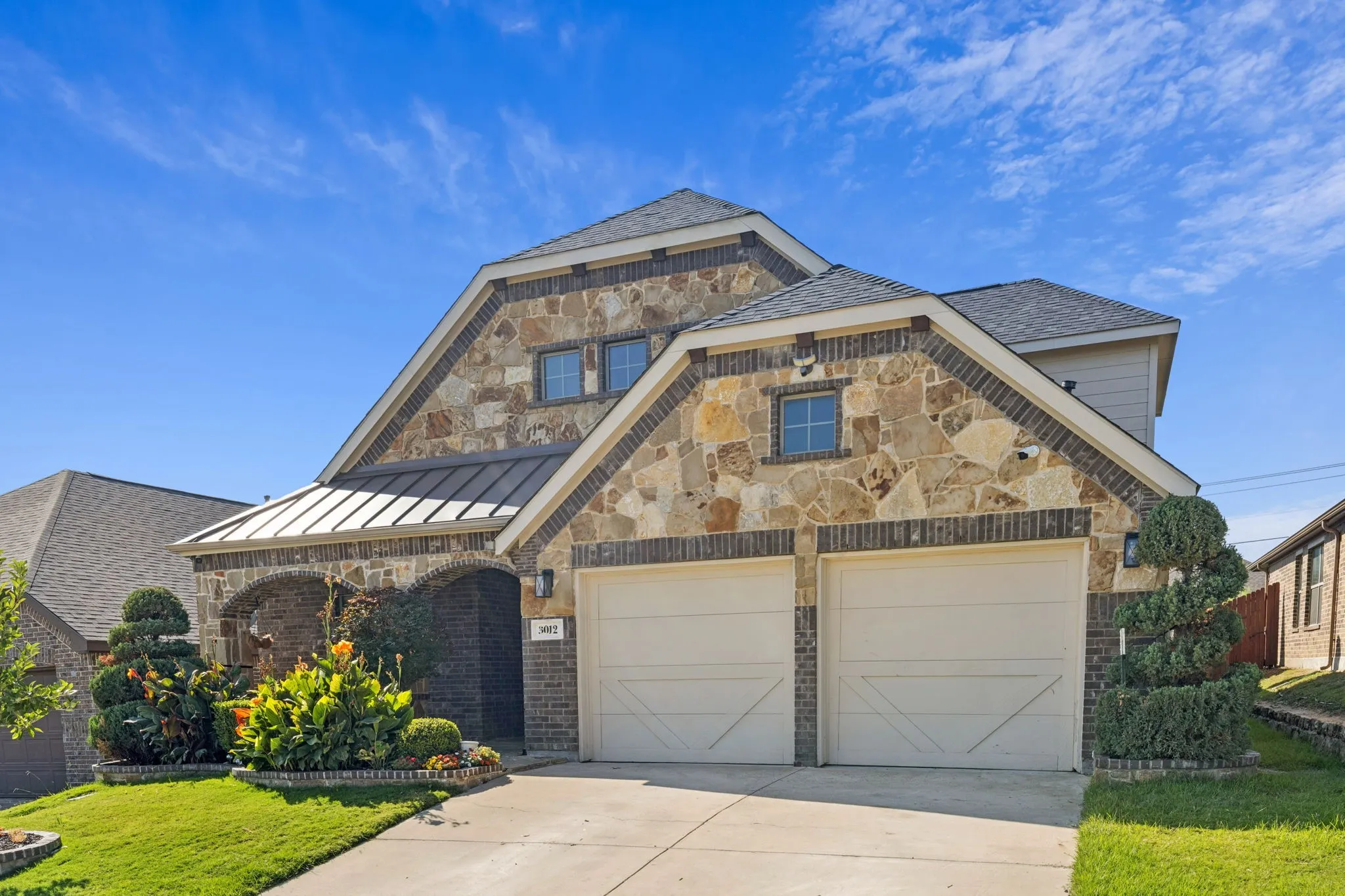 View of front of home featuring driveway, a front lawn, stone siding, and brick siding