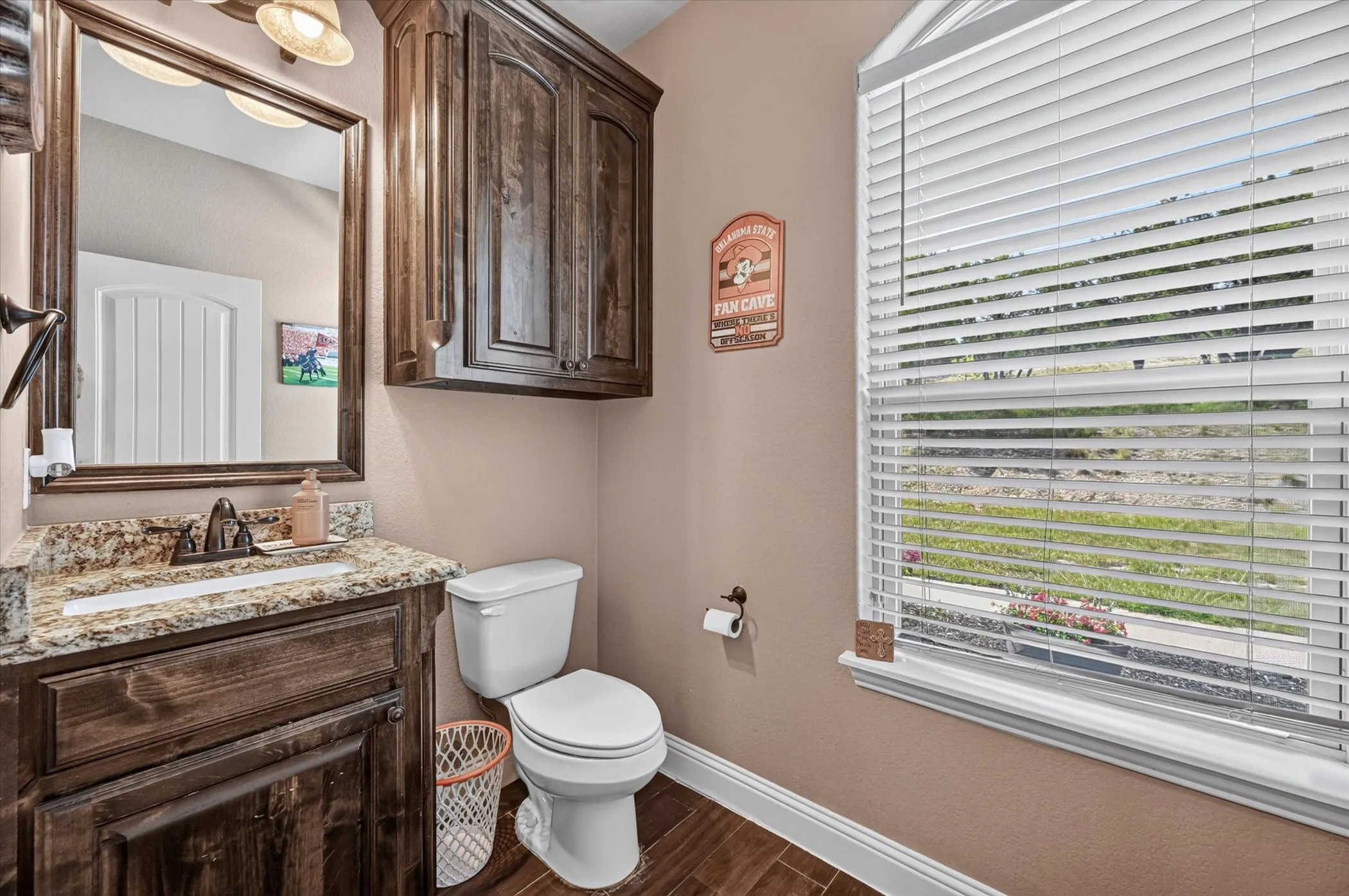 Bathroom featuring a dark wood-finish vanity with granite countertop, integrated sink, and an oil-rubbed bronze faucet