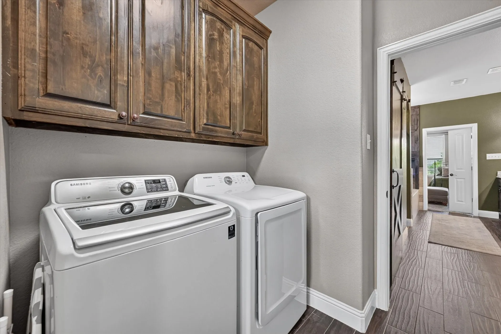 Laundry area featuring wood-finish flooring and upper wood cabinetry