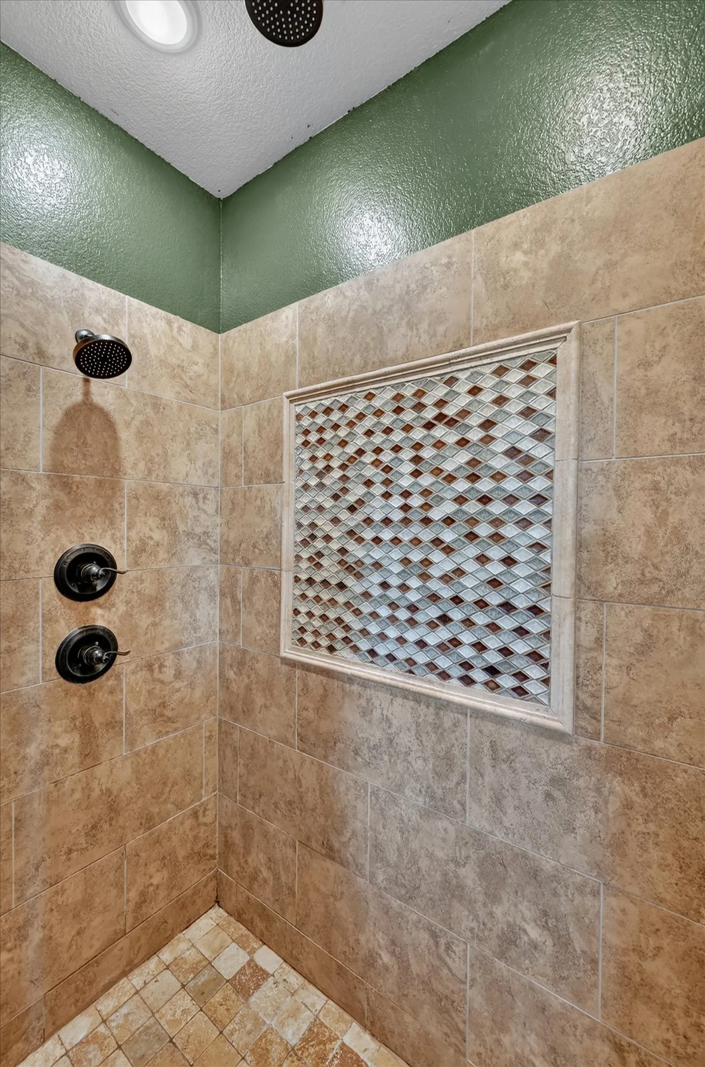 Shower with full-height tile walls and decorative mosaic tile accent niche