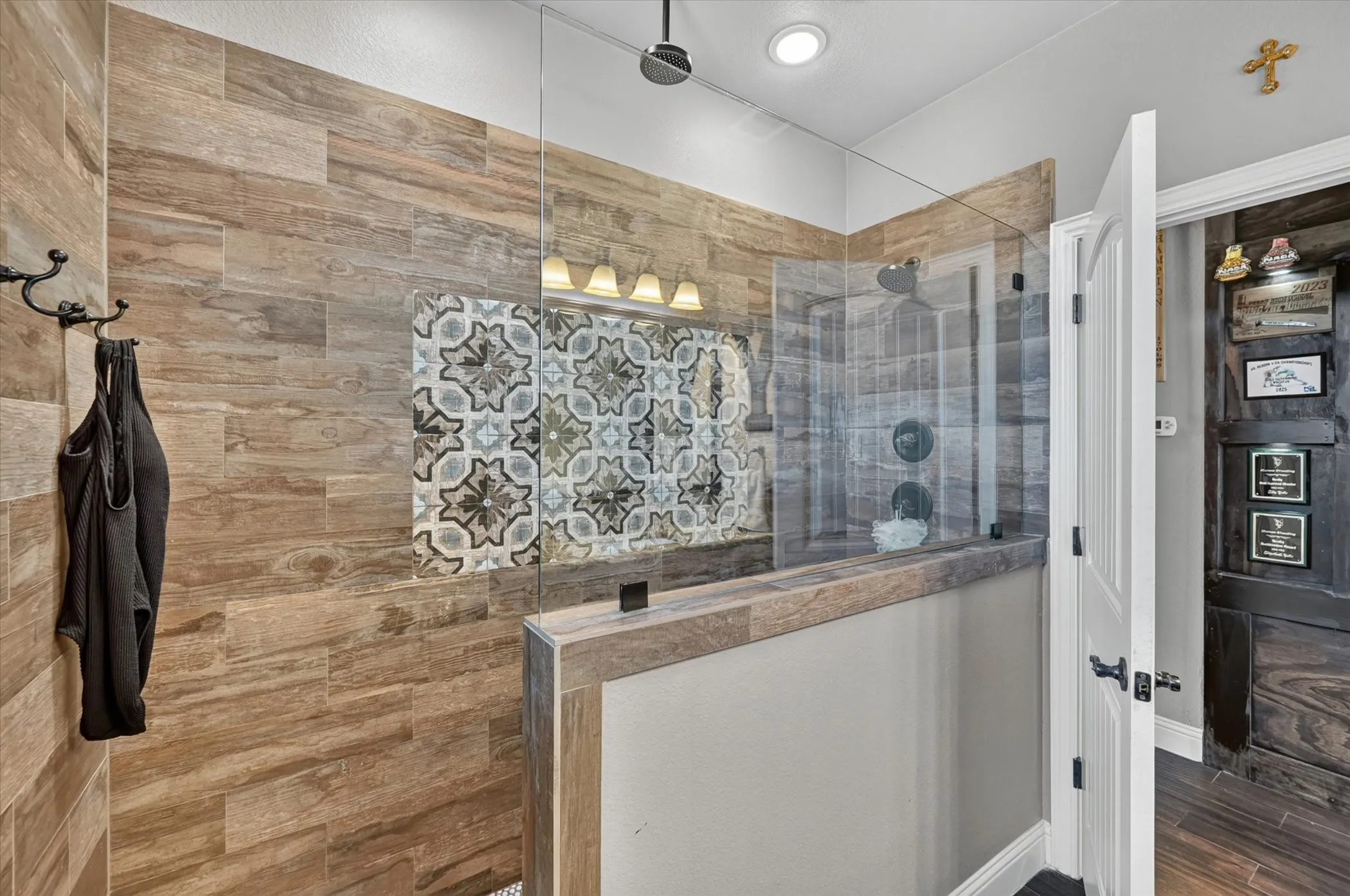 Spacious shower enclosure featuring full-height glass panels and a wood-look tile surround