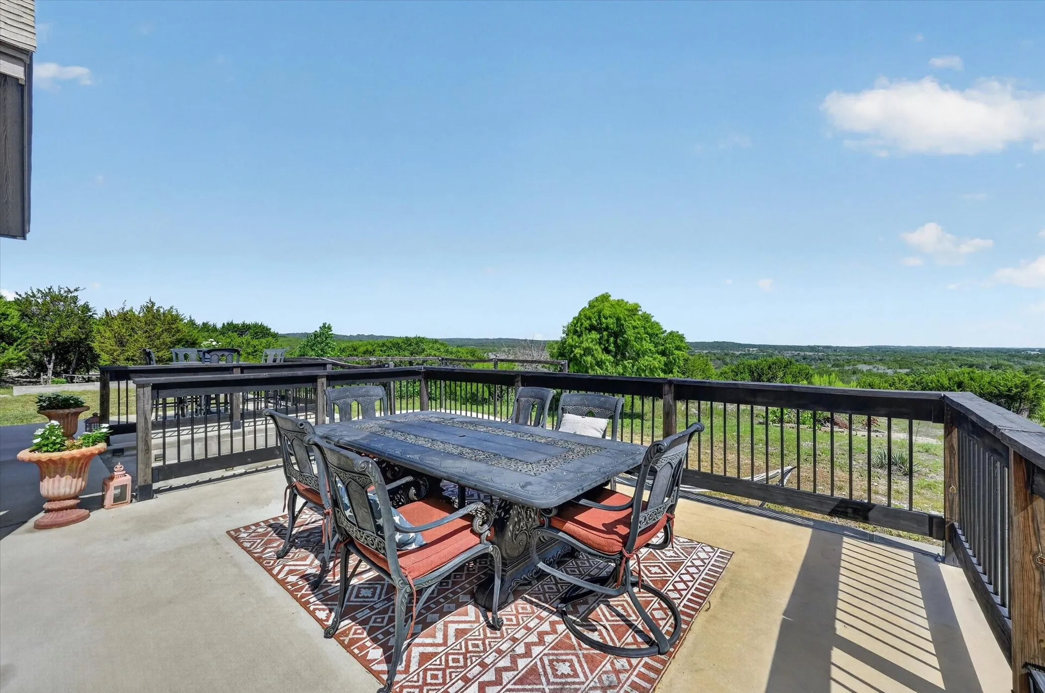 Spacious outdoor deck with a concrete surface and dark wood railings, offering expansive distant landscape scenery
