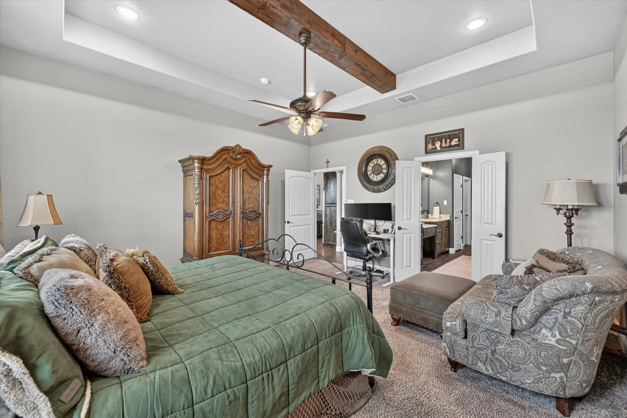 Spacious room featuring a tray ceiling with exposed wood beams, recessed lighting, and a ceiling fan