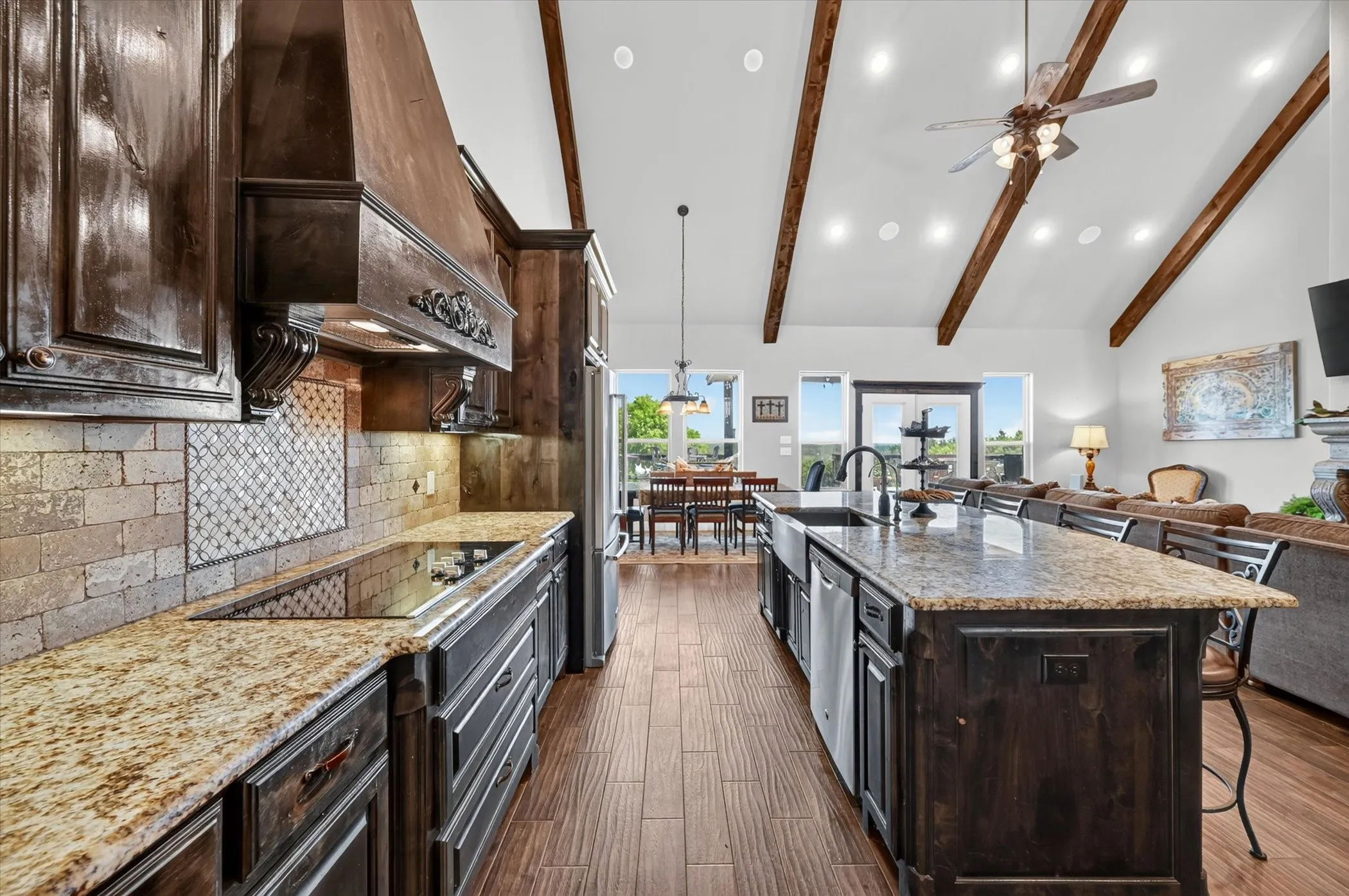 Kitchen featuring granite countertops, wood-finish flooring, custom cabinetry, and a tile backsplash with decorative inset