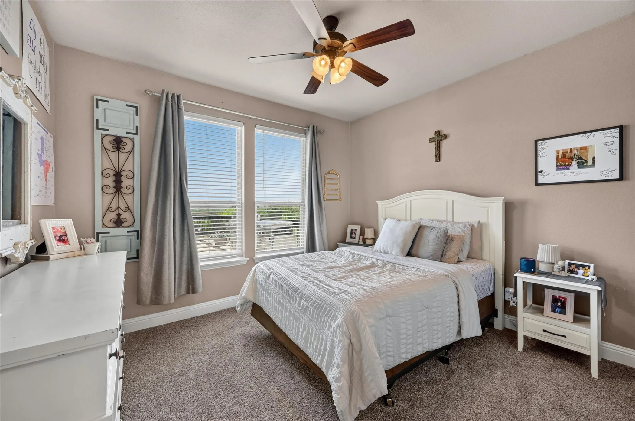 Carpeted room featuring a ceiling fan with integrated lighting, dual windows with horizontal blinds, and neutral wall tones