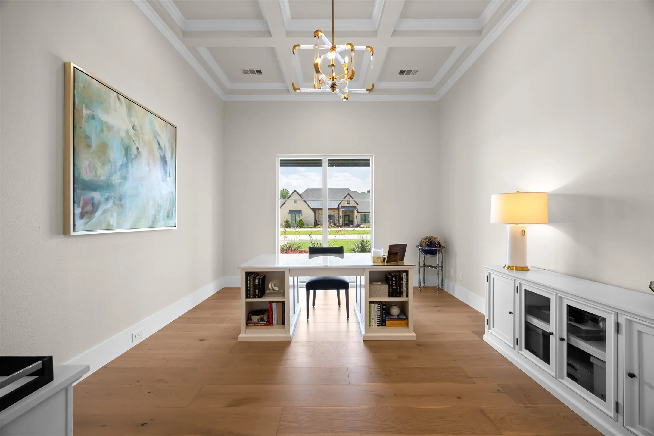 Behind sliding French doors, the study provides a quiet retreat for work or reflection, featuring soaring coffered ceilings, custom light fixture and picturesque views overlooking the front landscape