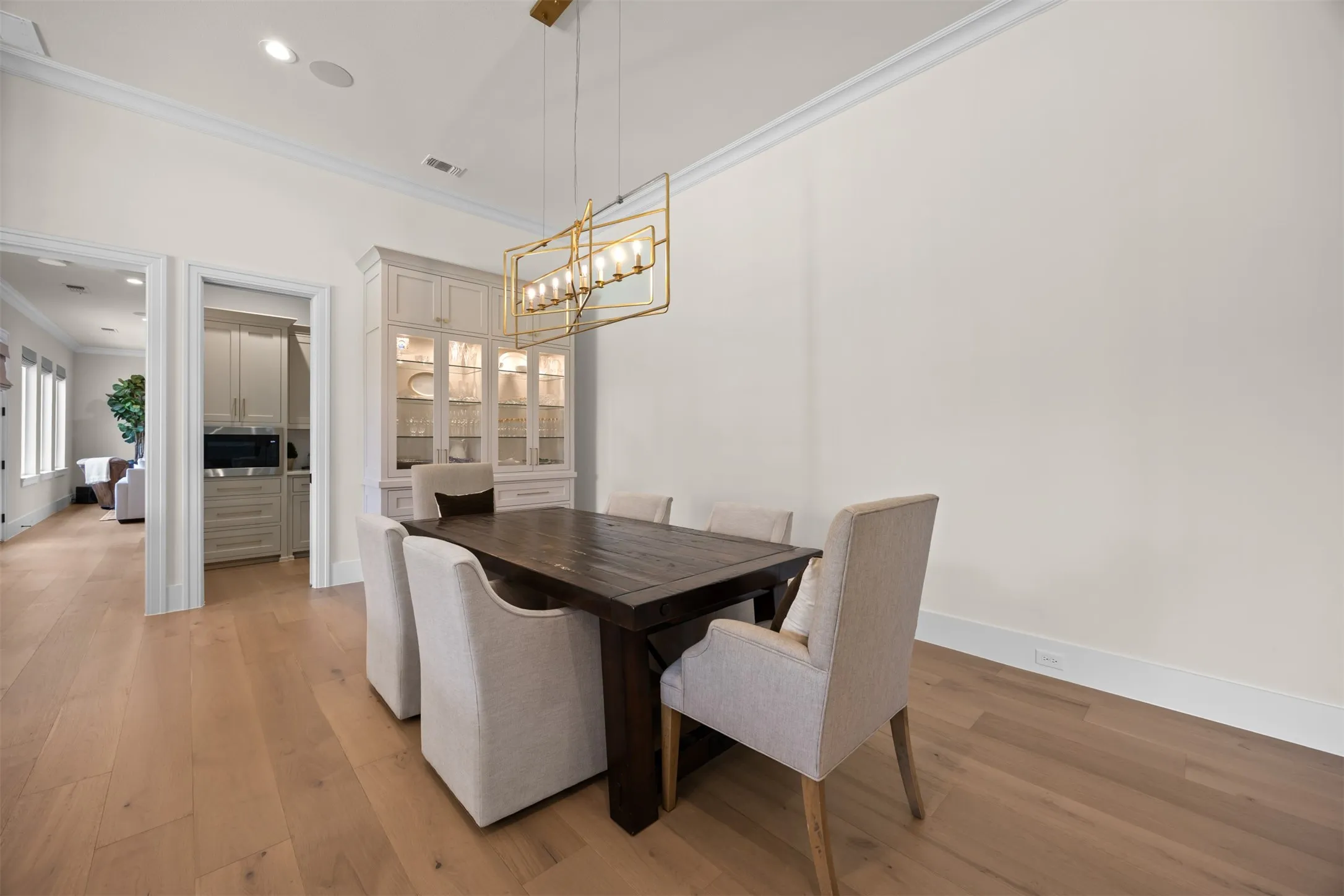 The elegant dining space can hold many different sizes and shapes of tables under the custom light fixture. You will love all the storage in the beautiful built in