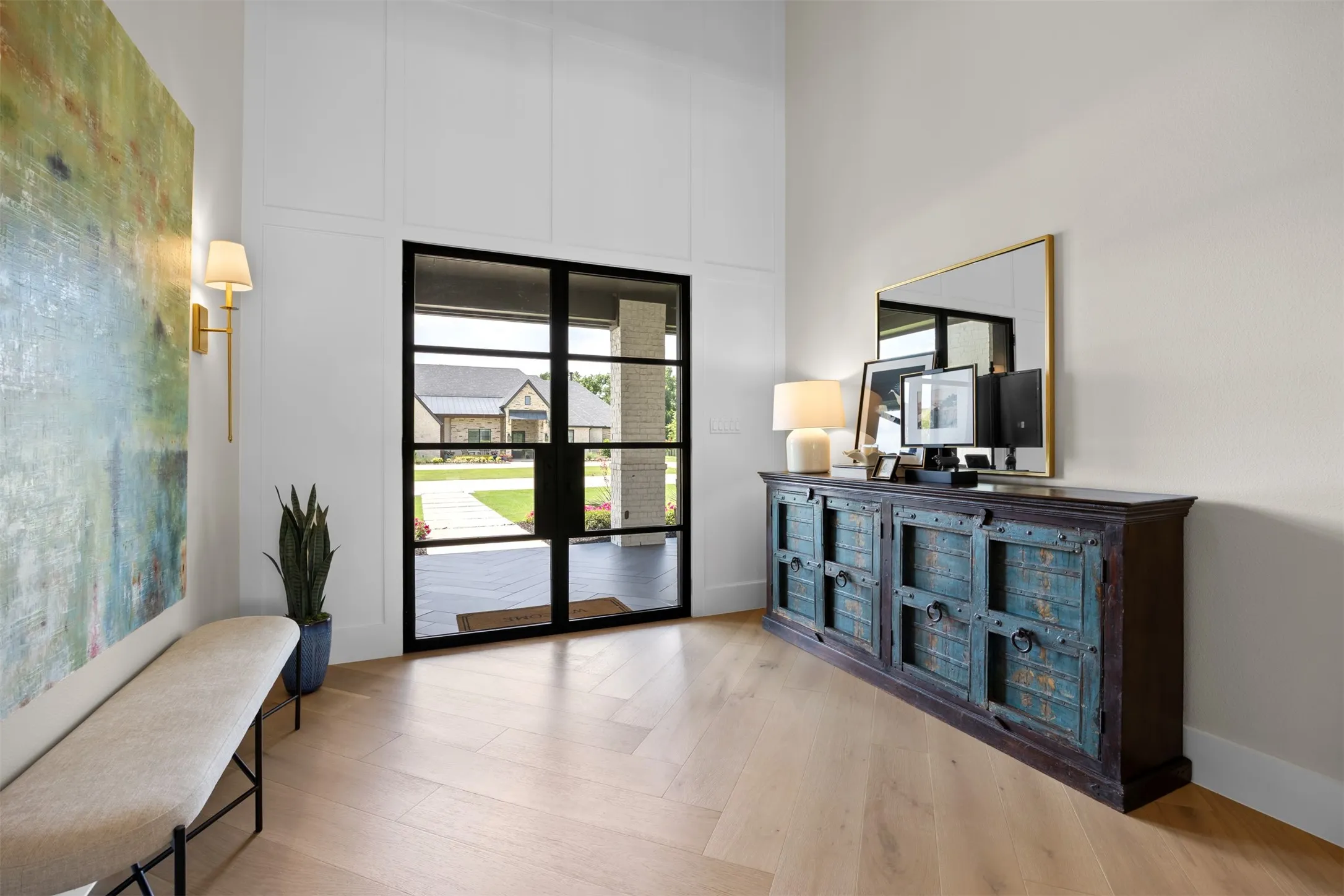 Stunning double door, soaring entrance with a herringbone patterned white oak, wide plank flooring & custom wall paneling. So elegant!