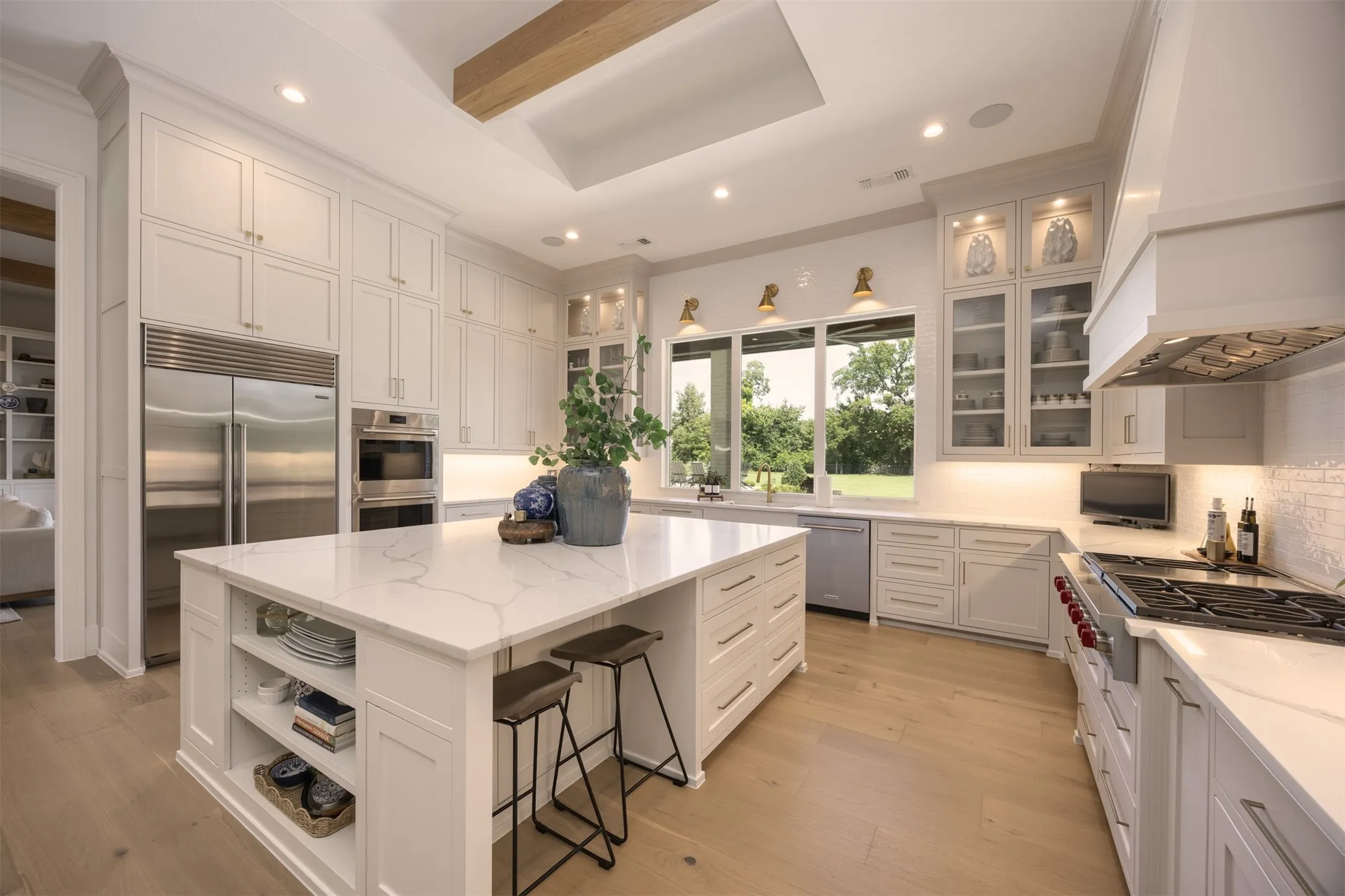 Anchored by an oversized island, this culinary masterpiece showcases premium Wolf stainless steel appliances, double ovens, a SubZero refrigerator, custom cabinetry & beautiful lighting.