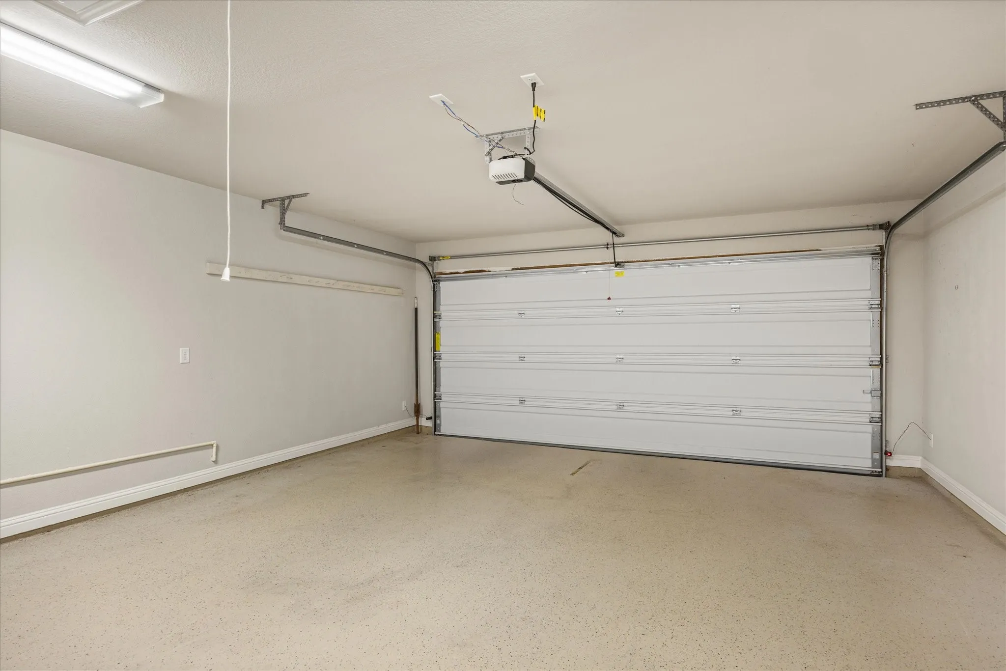 Spacious garage featuring an epoxy coated  floor, overhead lighting, and an automatic garage door opener