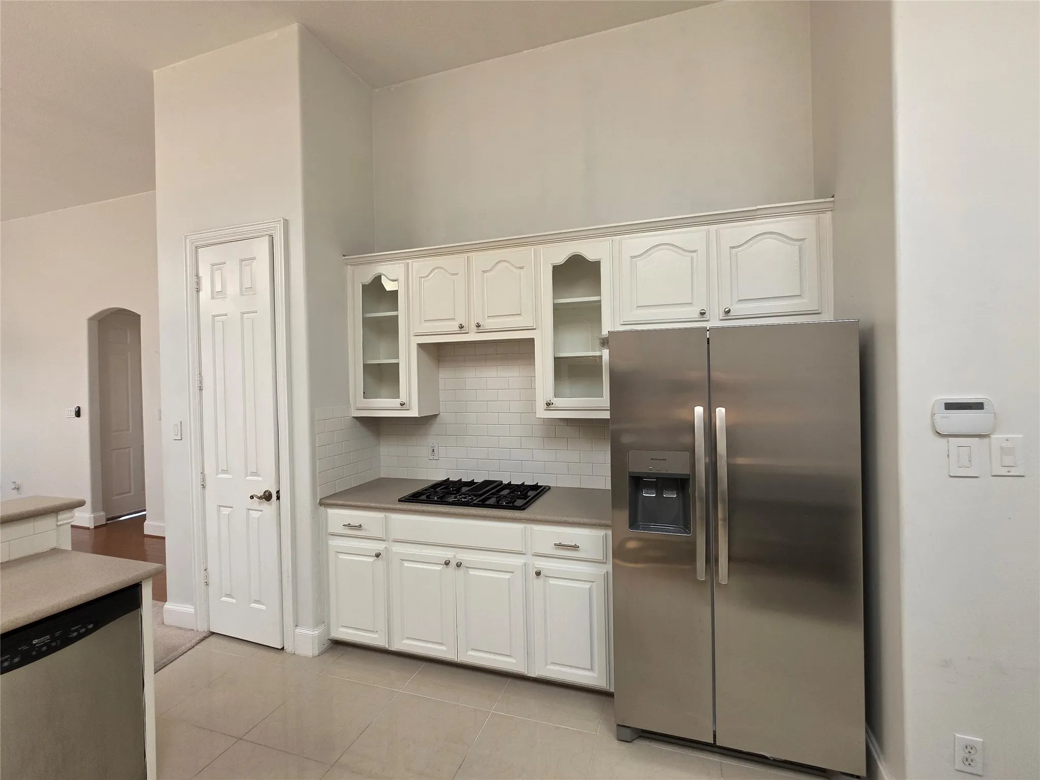 Kitchen featuring a stainless steel side-by-side refrigerator, white cabinetry, subway tile backsplash, and a built-in gas cooktop