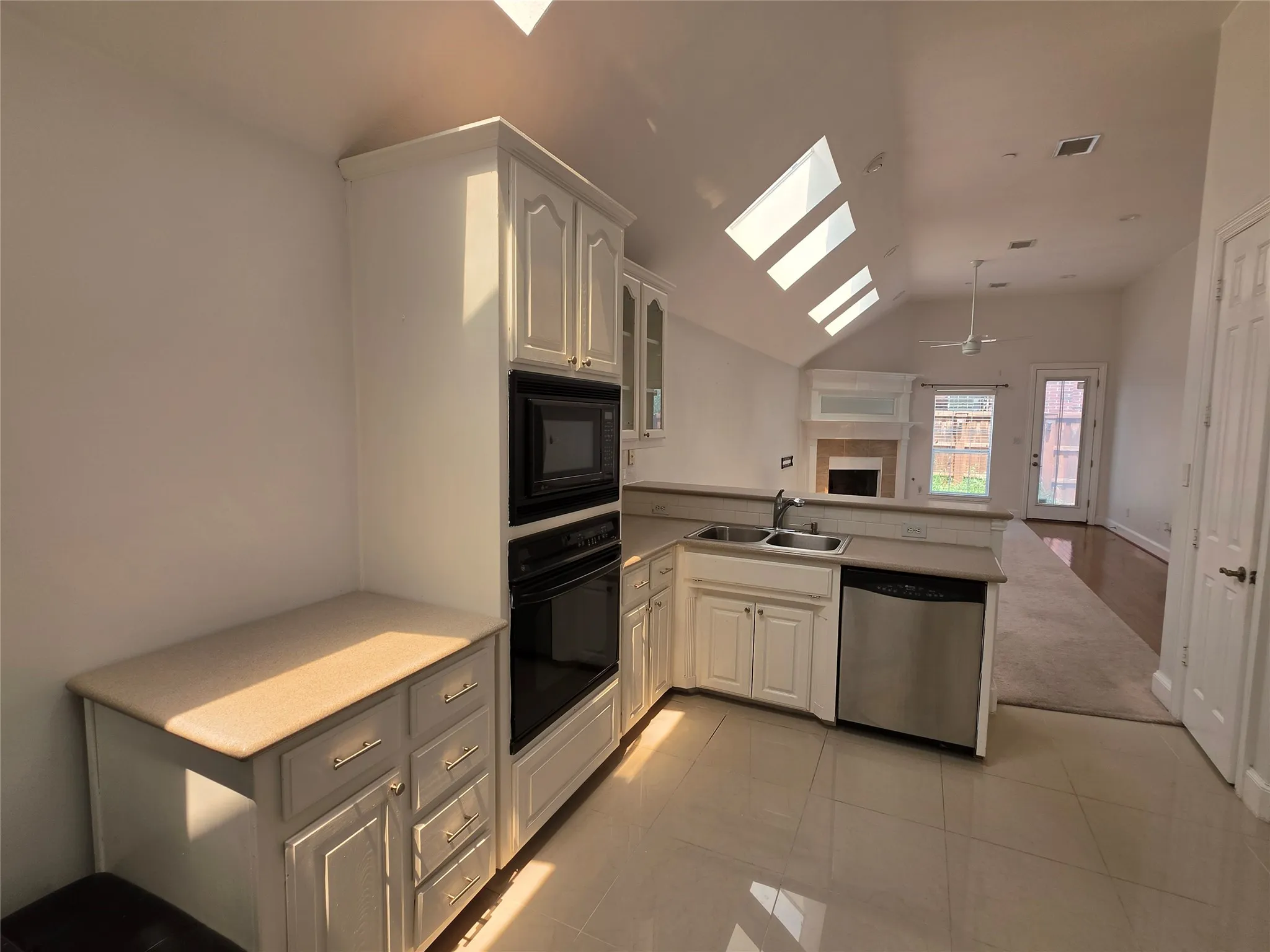 Kitchen featuring white cabinetry, built-in microwave and oven, a stainless steel dishwasher, and a double basin sink