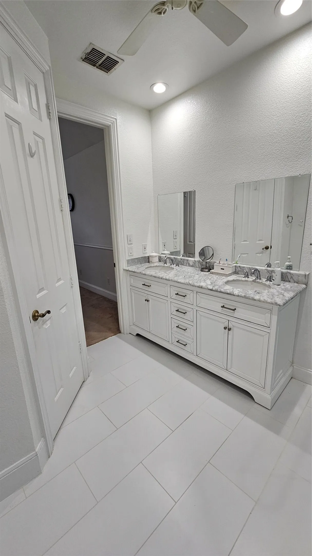Dual vanity featuring white cabinetry and a light-colored stone countertop with integrated sinks