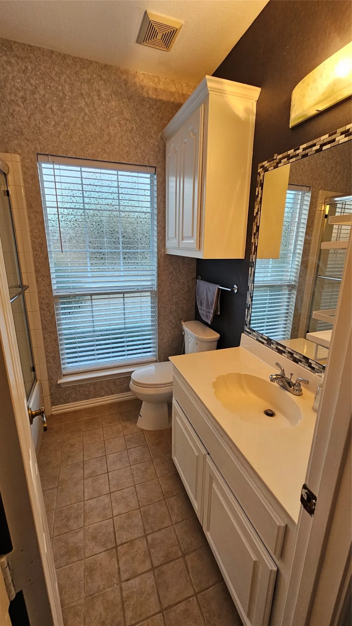 Bathroom featuring a white vanity with integrated sink, tiled flooring, built-in medicine cabinet, and a window with blinds