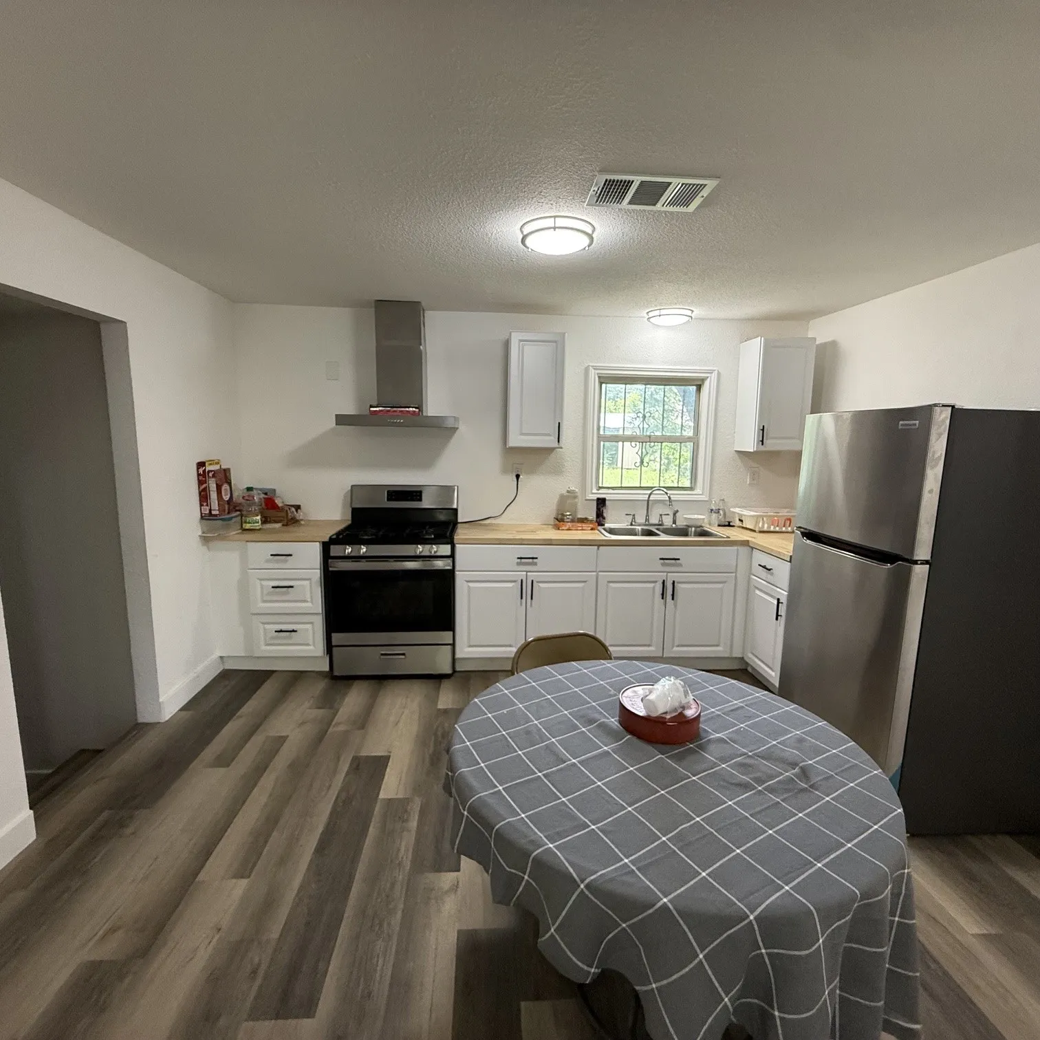 Kitchen featuring wood-finish flooring and white cabinetry with dark hardware