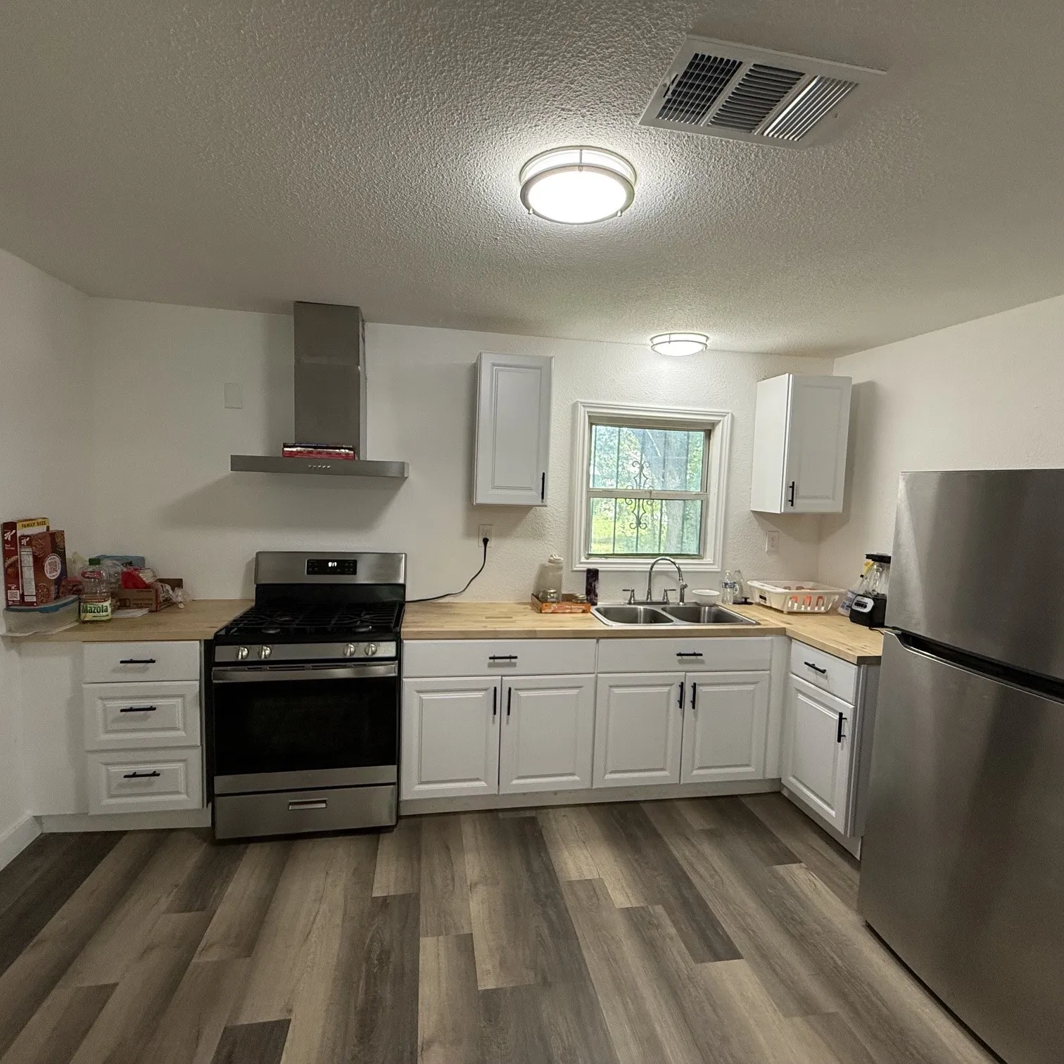 Kitchen featuring wood-finish flooring and white cabinetry