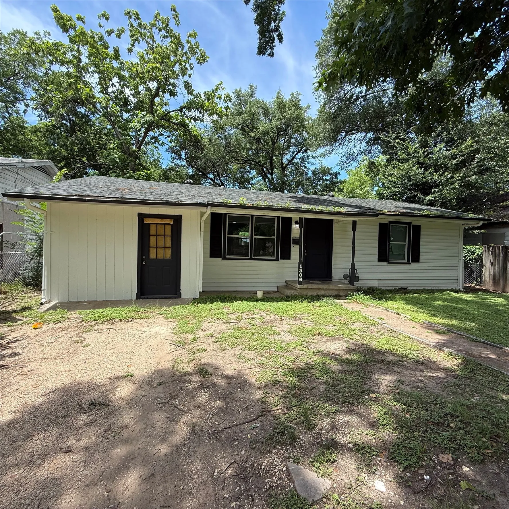 White exterior siding with black trim, a black front door, and a black secondary door with a grid-patterned window