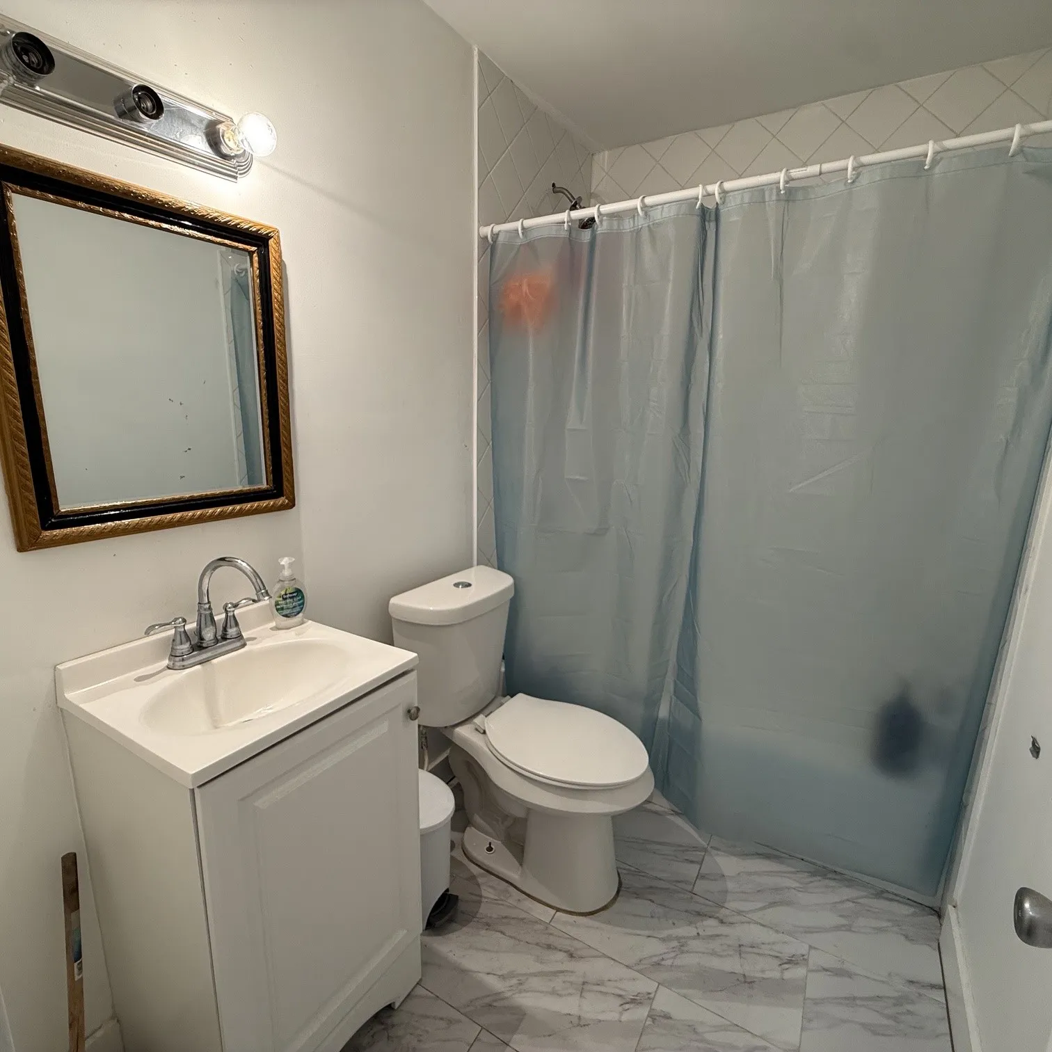 Bathroom featuring a white vanity with integrated sink, chrome faucet, and ornate gold-framed mirror