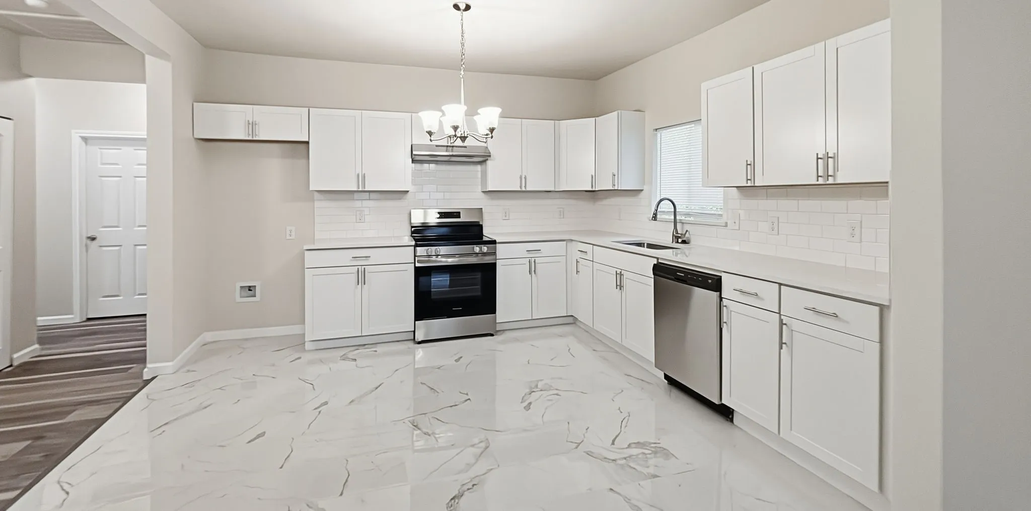 Modern kitchen featuring white cabinetry, quartz countertops, subway tile backsplash, and stainless steel appliances