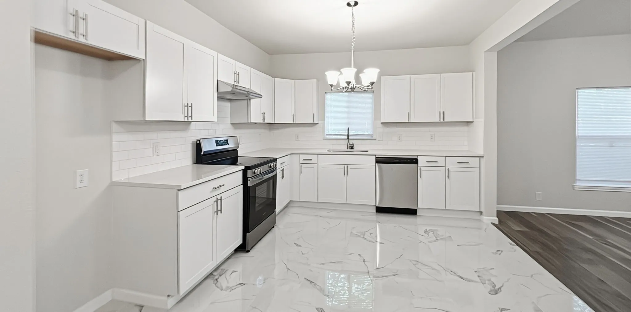Modern kitchen featuring white cabinetry, light countertops, subway tile backsplash, and large format marble-look flooring