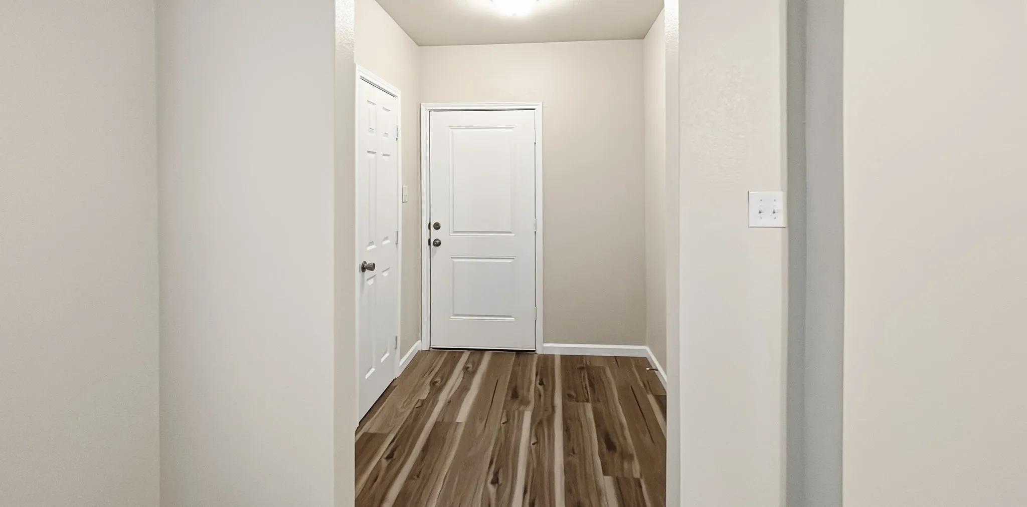 Entryway featuring wood-finish flooring, light-toned walls, and white trim