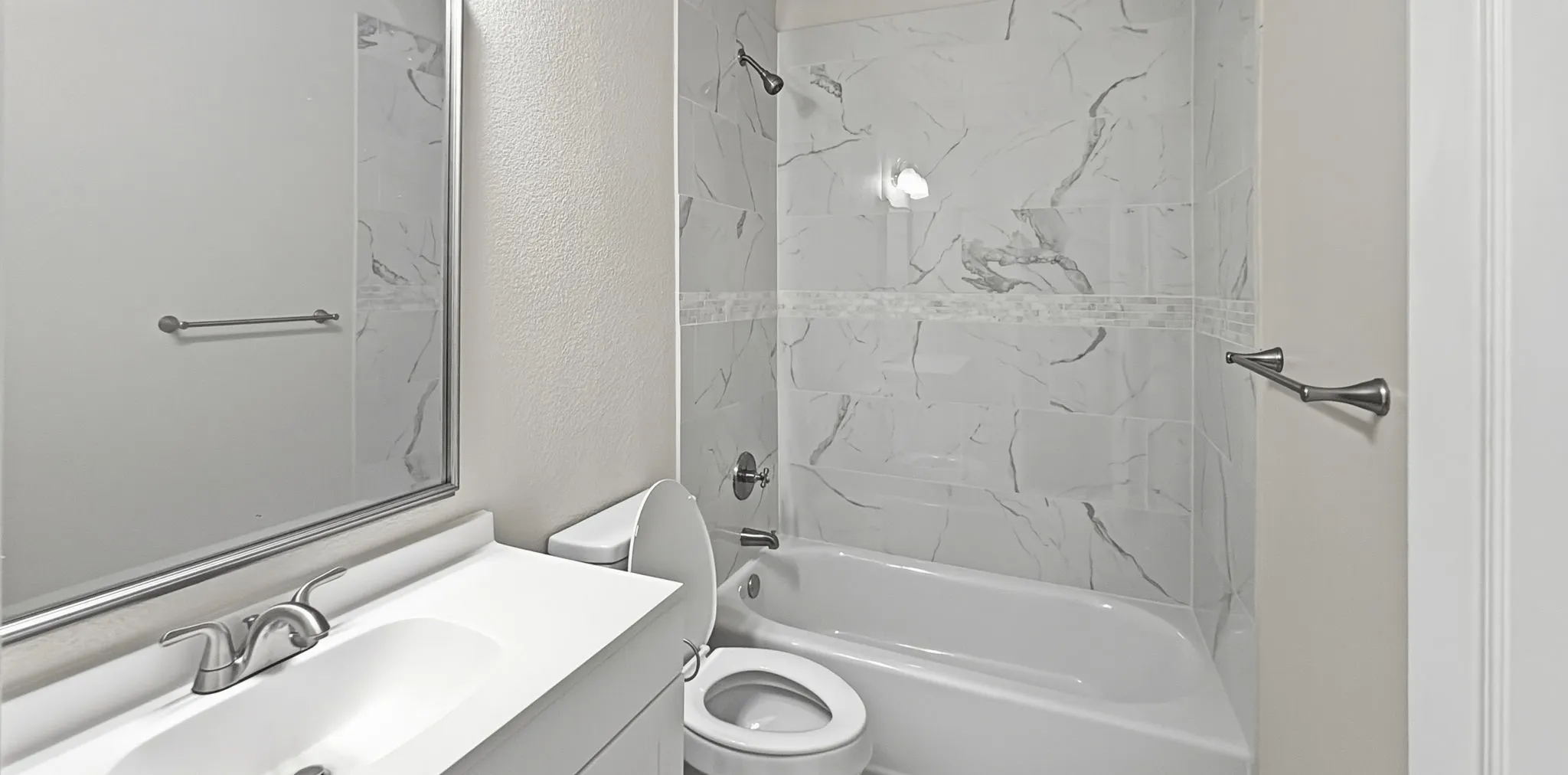 Bathroom featuring a white vanity with an integrated sink, brushed nickel faucet, and framed mirror