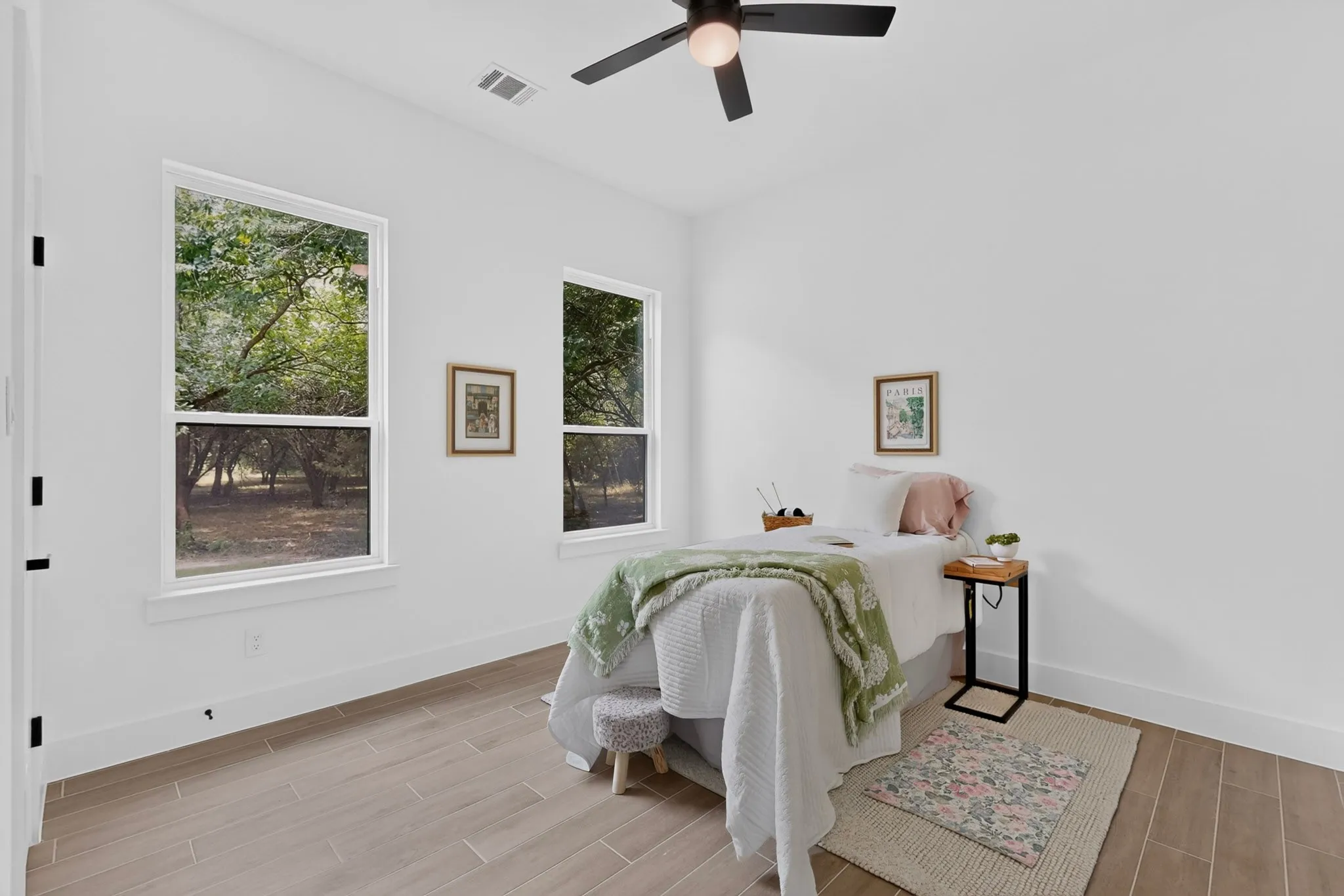 Bright interior room featuring wood-finish flooring, white walls, and a ceiling fan