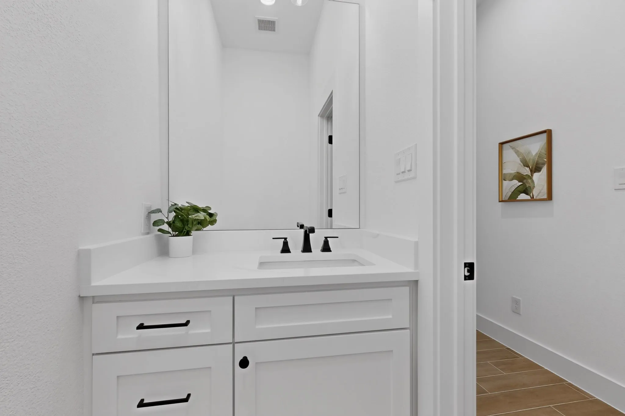 White vanity with a rectangular undermount sink, a white countertop, and matte black hardware