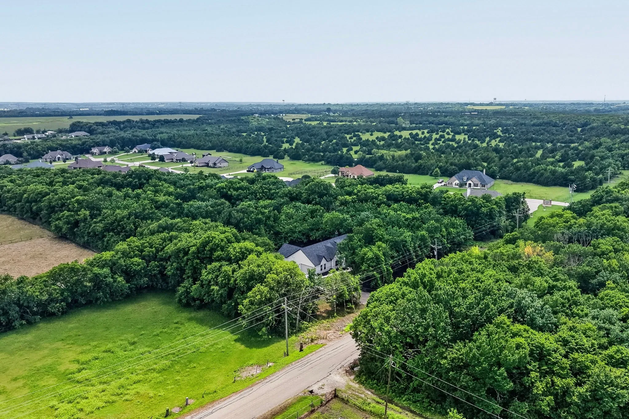 Rural landscape featuring extensive tree cover and a scattered residential development