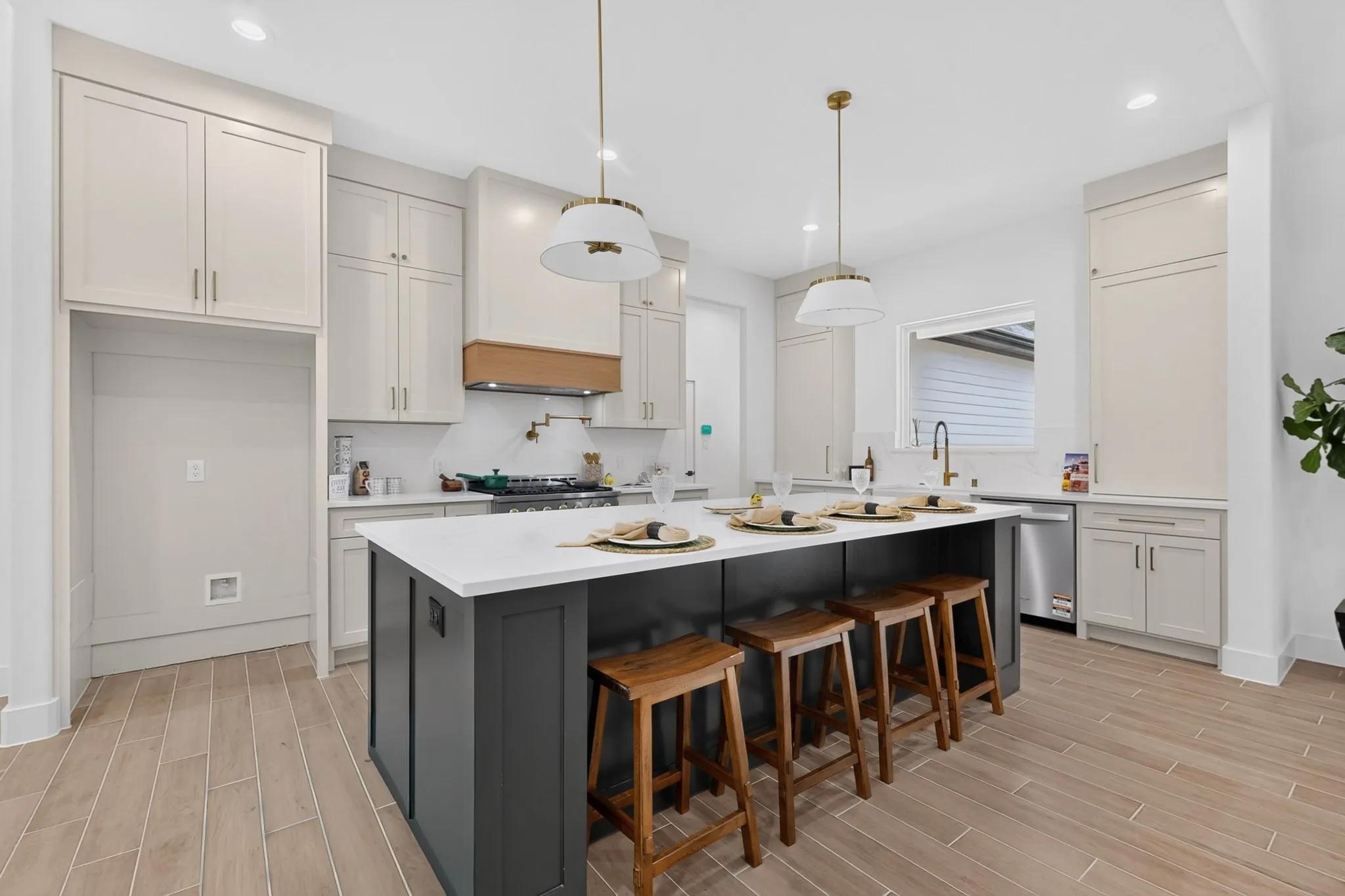 Kitchen featuring a central island with countertop seating, light-toned upper cabinetry, dark-toned lower island cabinetry, a built-in range, and wood-finish flooring
