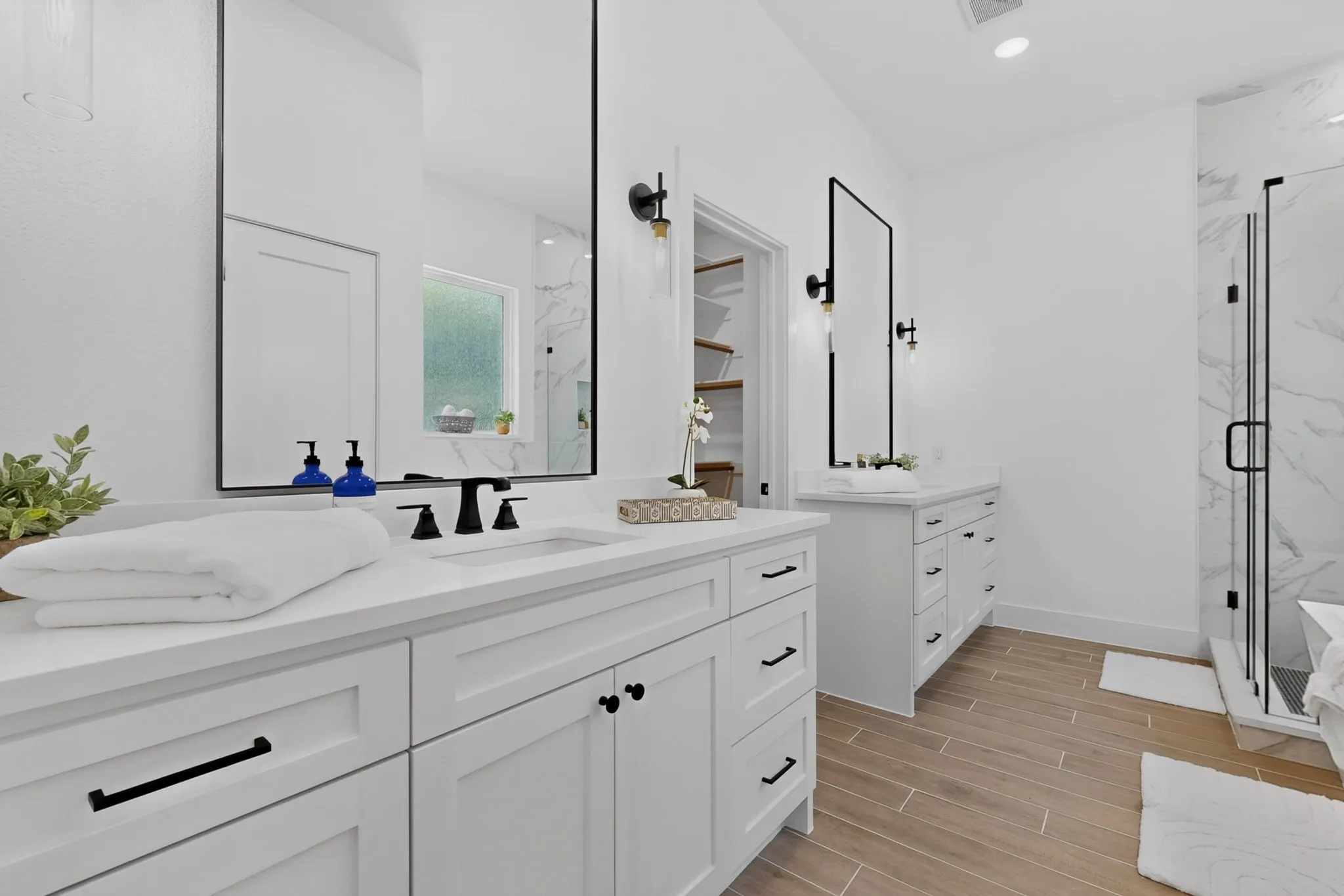 Dual vanity with white cabinetry, quartz countertops, black hardware, and framed mirrors