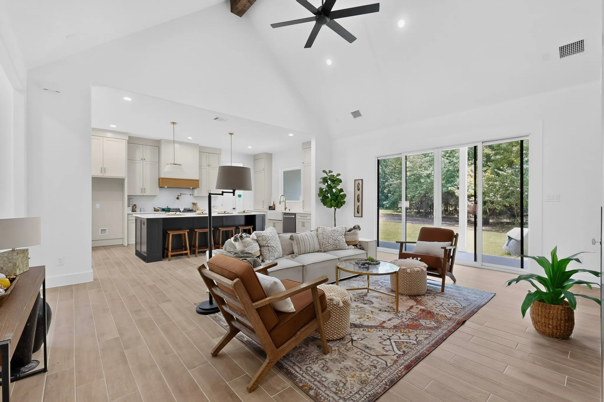 Spacious open-concept living area featuring high vaulted ceilings, recessed lighting, and wood-finish flooring