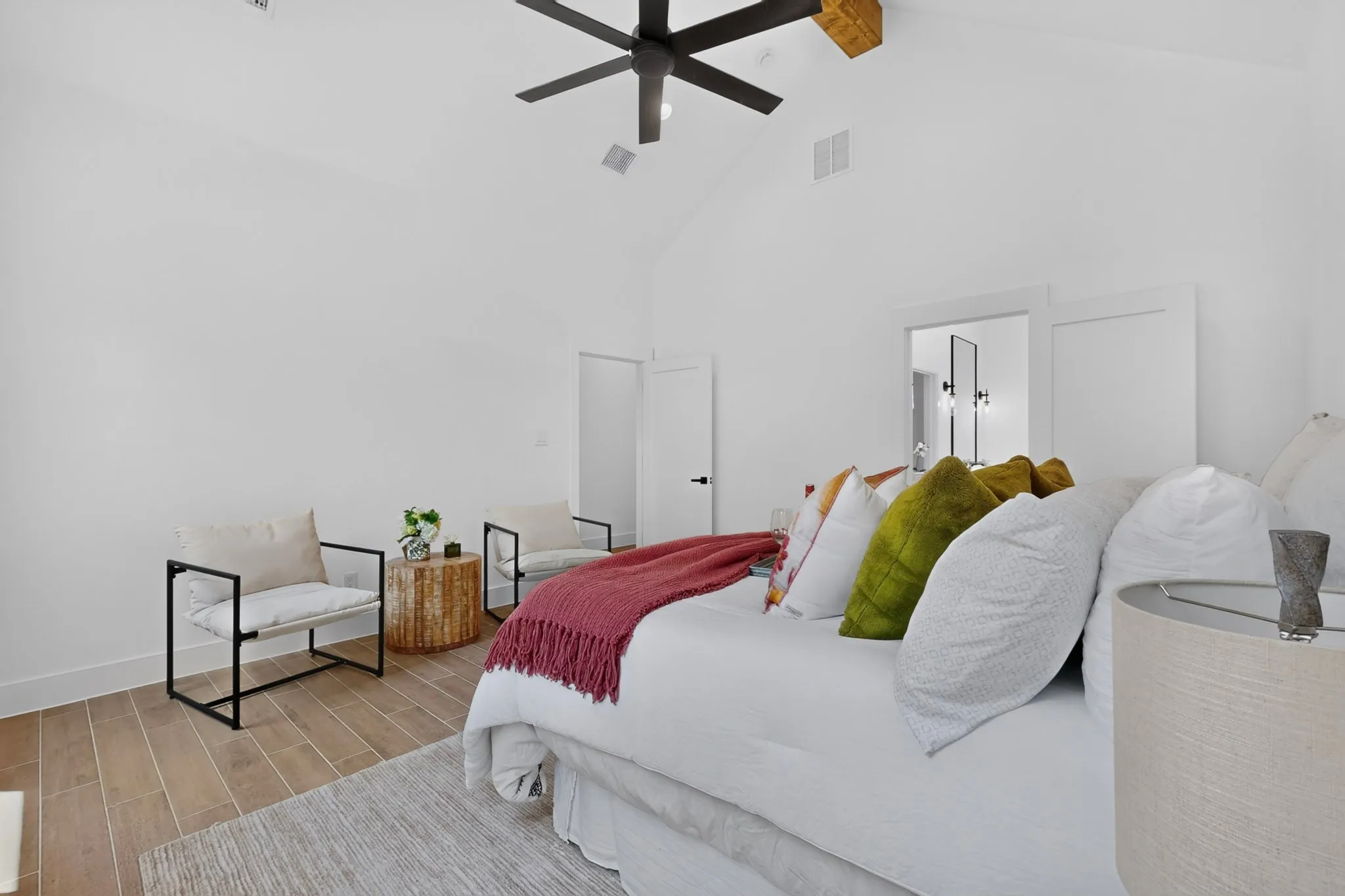 Vaulted ceiling room with wood-finish flooring, a contemporary ceiling fan, and white doors