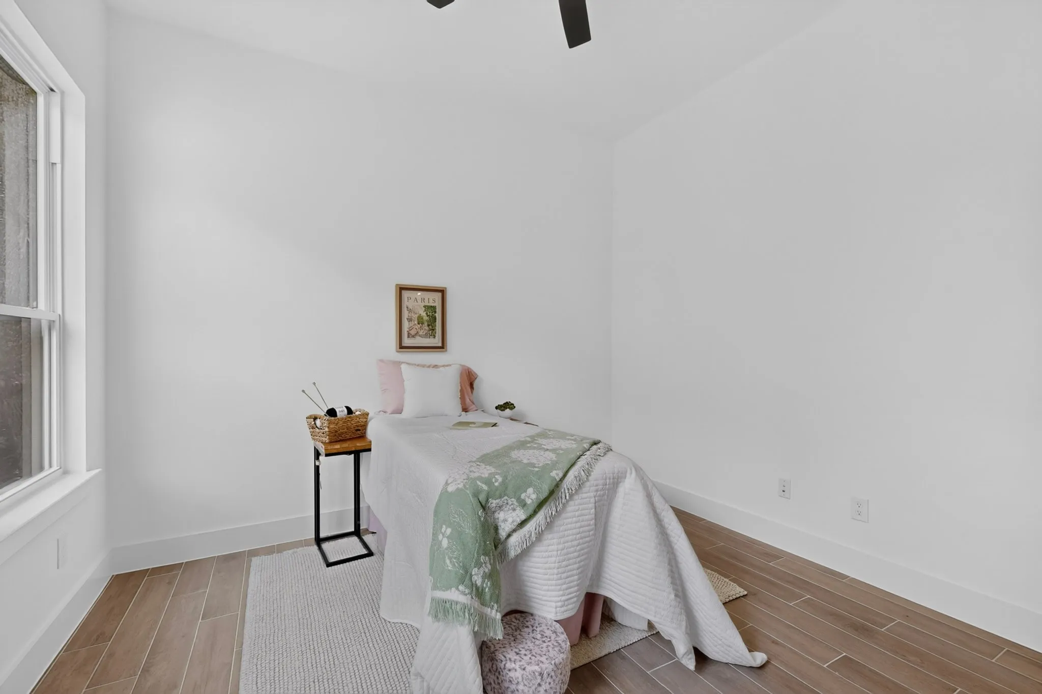 Interior room featuring light wood-finish flooring, white walls, and a ceiling fan