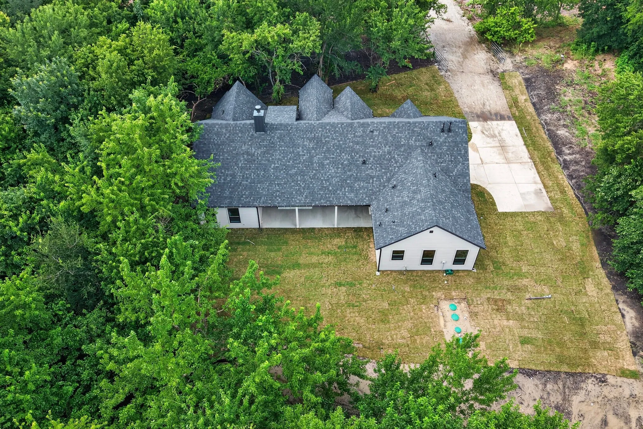 Aerial perspective showcasing a single-story residence with a dark shingle roof and light-colored siding