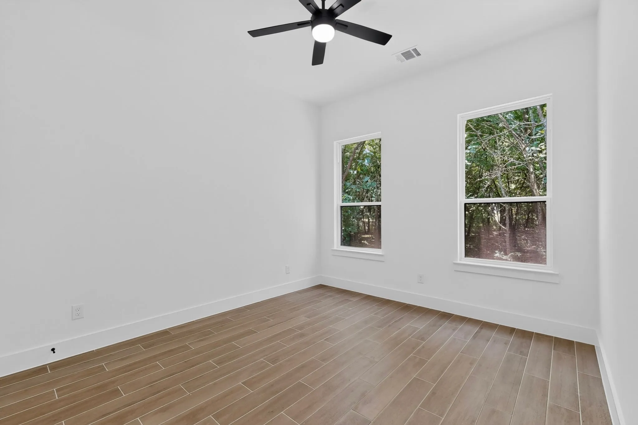 Bright room featuring wood-look tile flooring and two windows with white trim