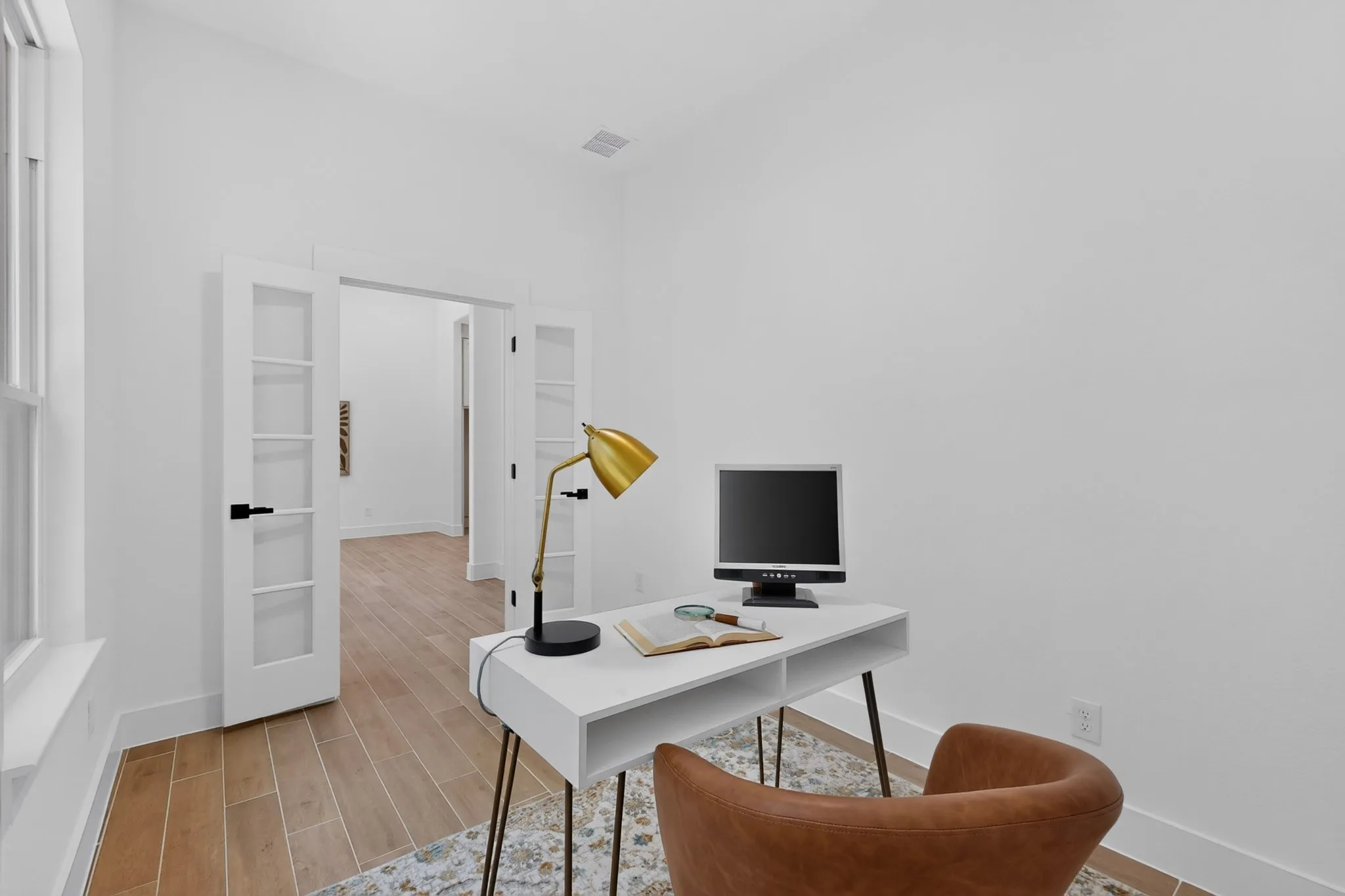 Spacious room featuring wood-finish flooring, white walls, and bright white trim