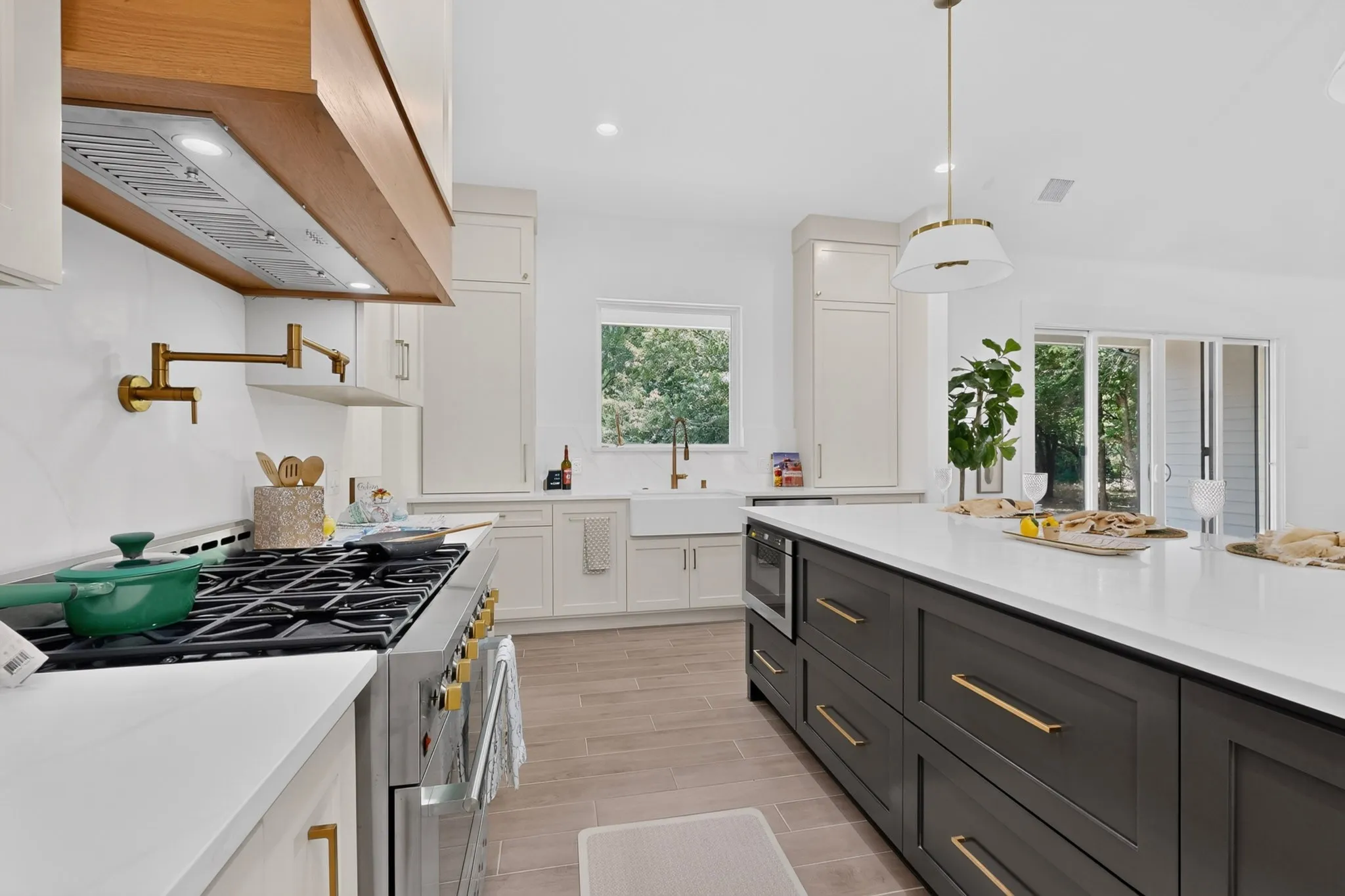 Spacious kitchen featuring a large central island with integrated microwave, white countertops, built-in stainless steel range, and gold-finish fixtures