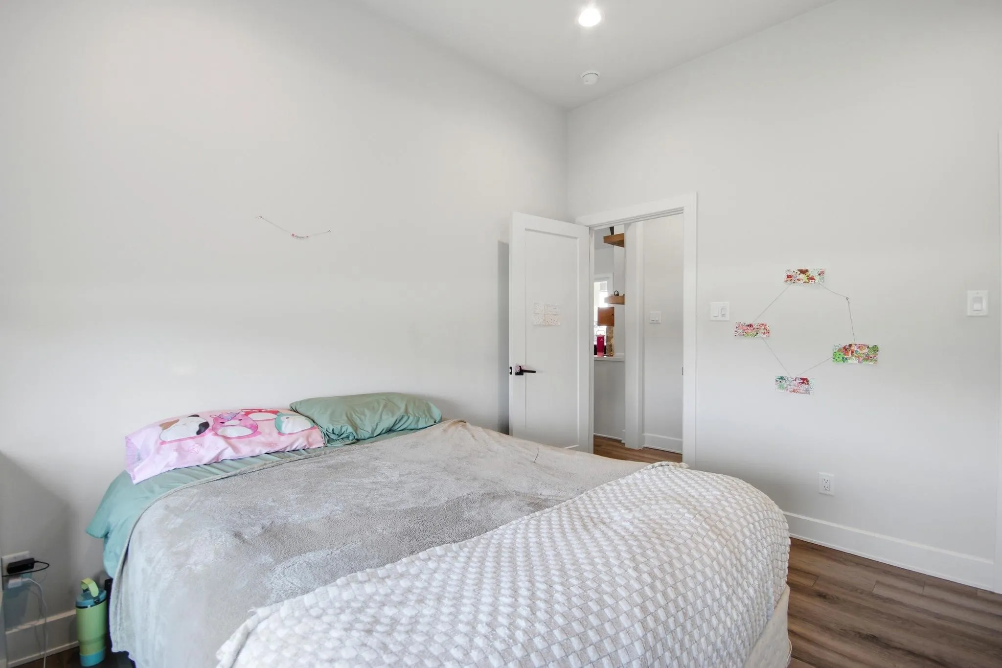 Spacious interior room featuring light-toned walls, recessed lighting, wood-finish flooring, white baseboards, and a white interior door with a black​​‌​​​​‌​​‌‌​‌‌​​​‌‌​‌​‌​‌​​​‌​​ handle
