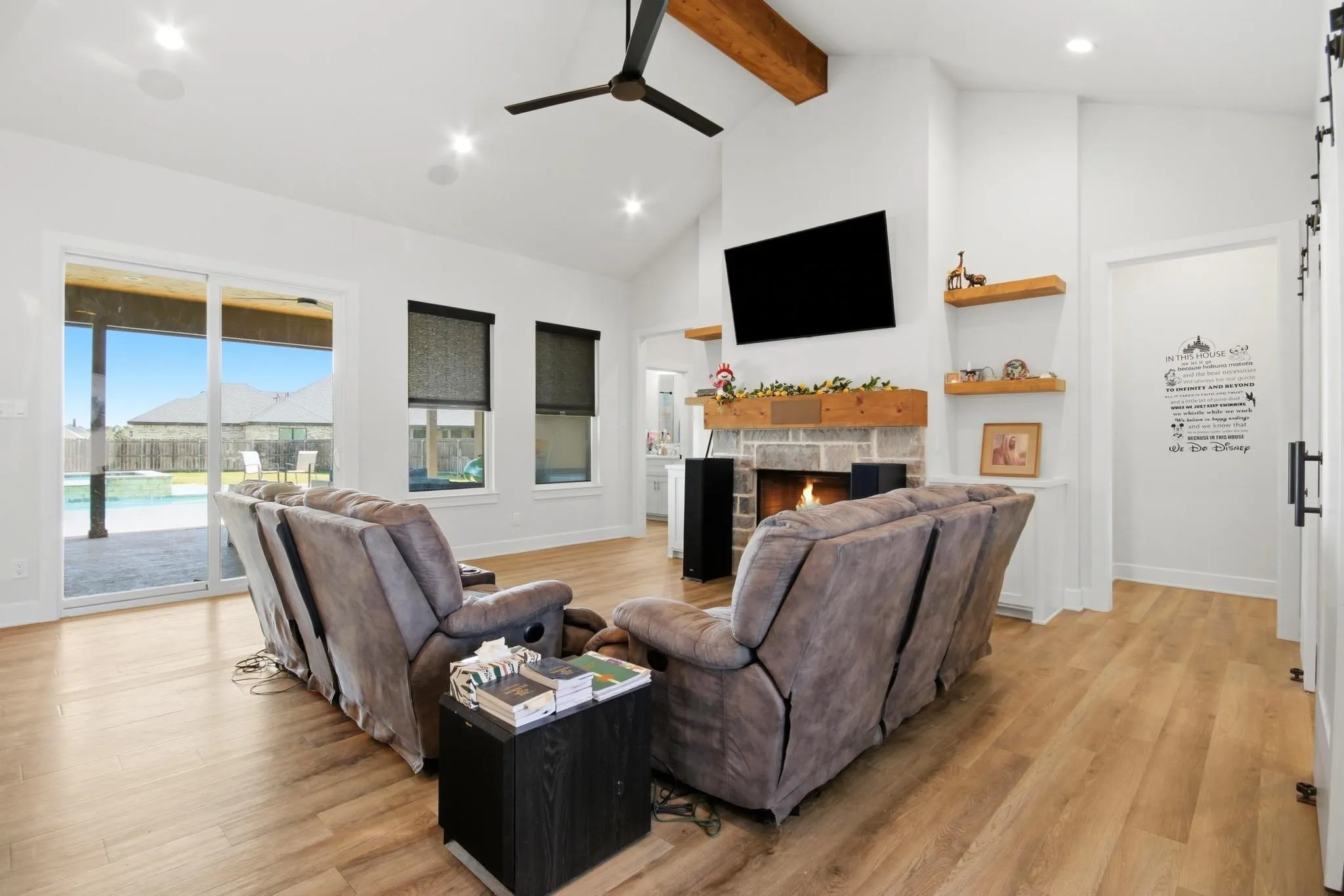 Spacious living area featuring a vaulted ceiling with exposed wood beams, a black ceiling fan, and recessed lighting