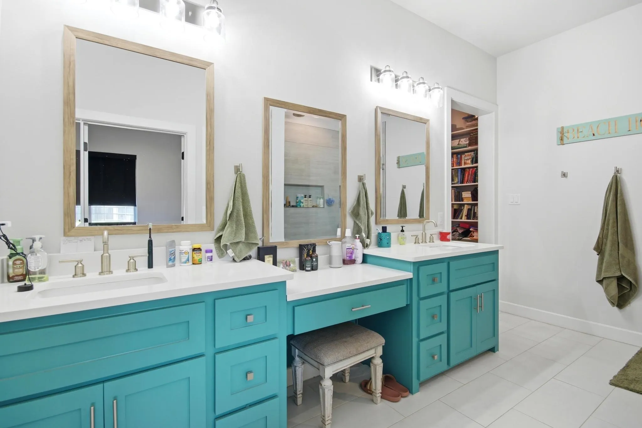 Dual vanity with teal cabinetry, white countertops, and brushed nickel fixtures