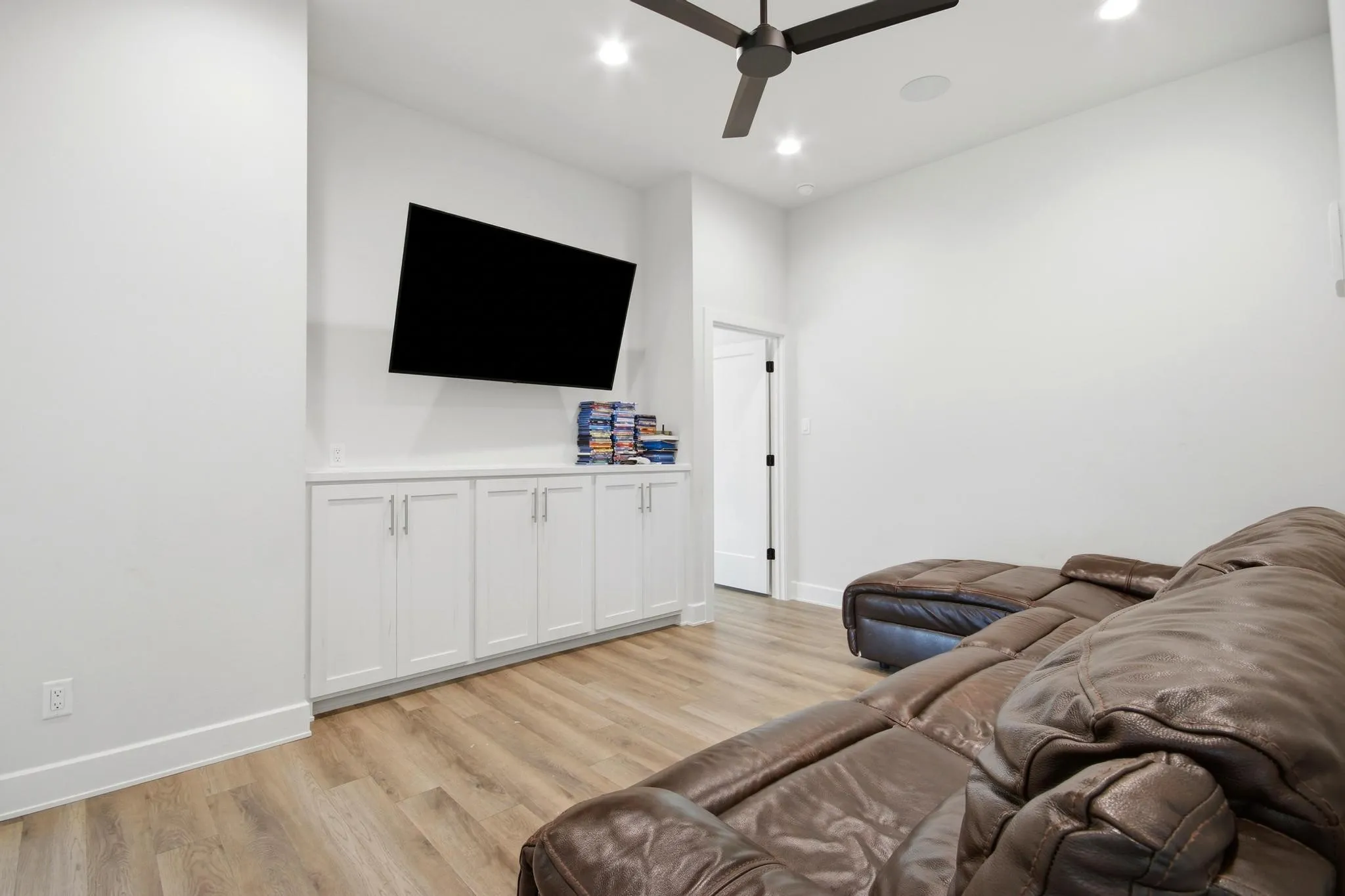 Media room featuring wood-finish flooring, recessed lighting, and a contemporary ceiling fan