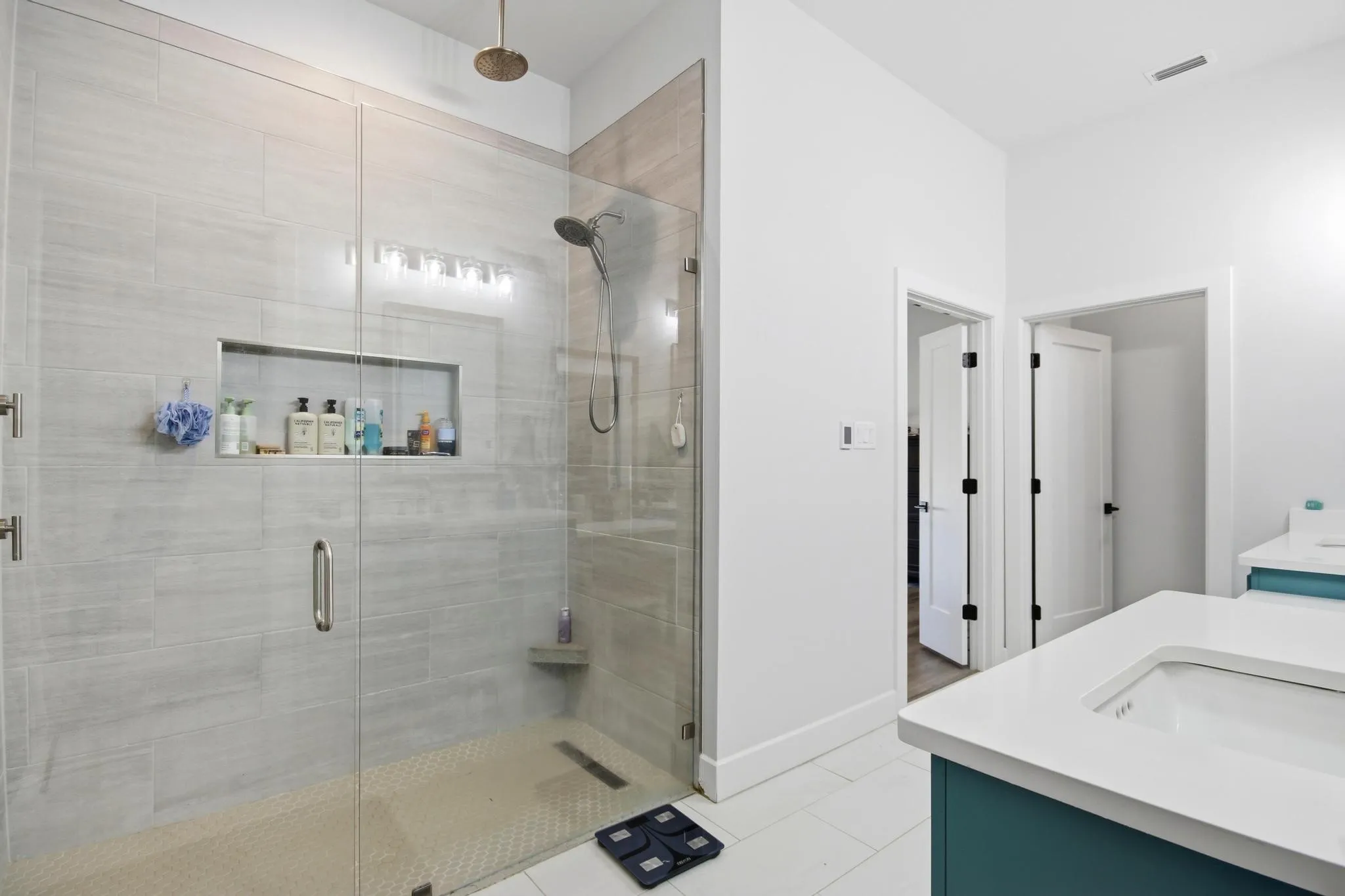 Glass-enclosed shower featuring large format tile walls and a built-in niche