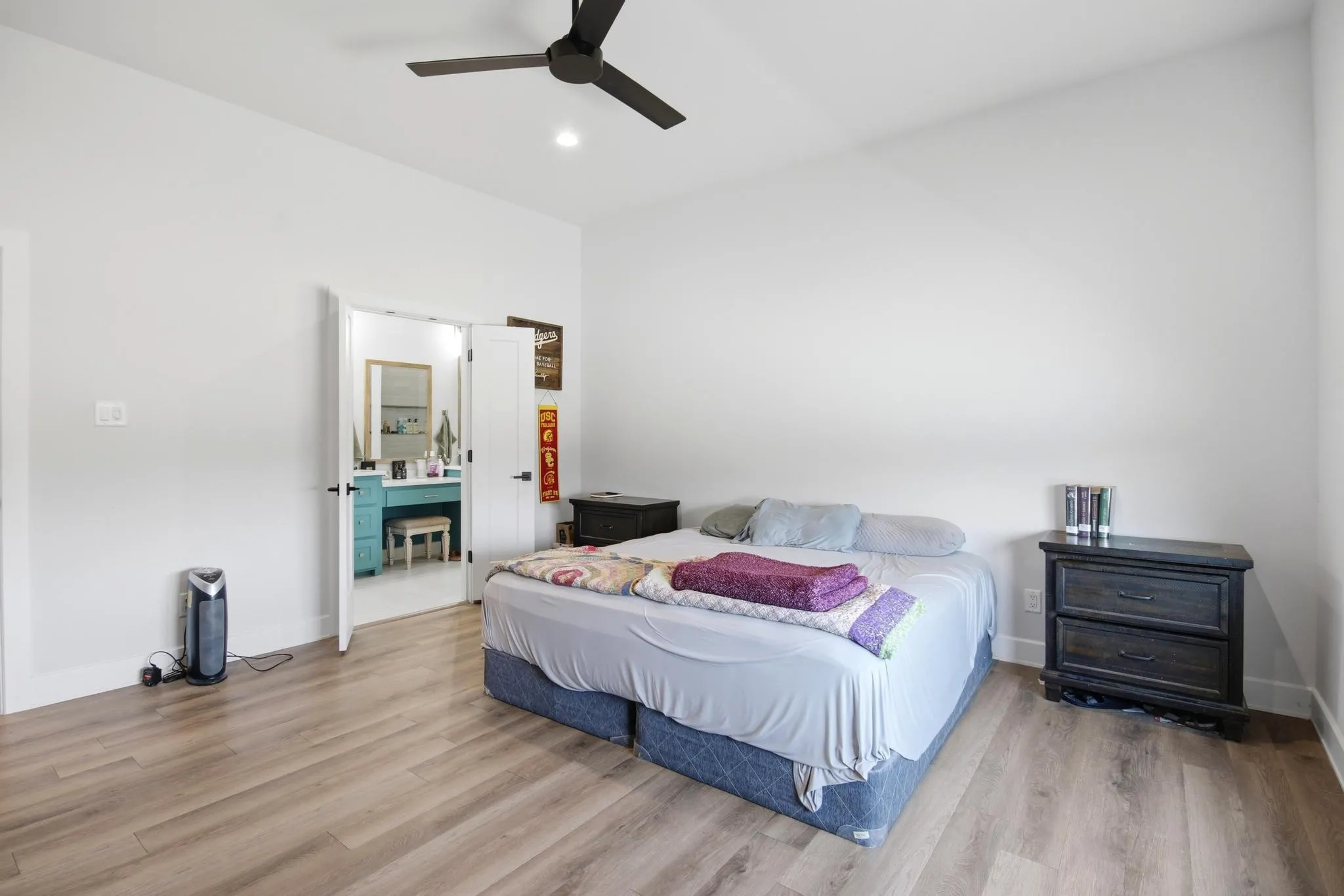 Vaulted ceiling bedroom featuring wood-finish flooring and a contemporary black ceiling fan