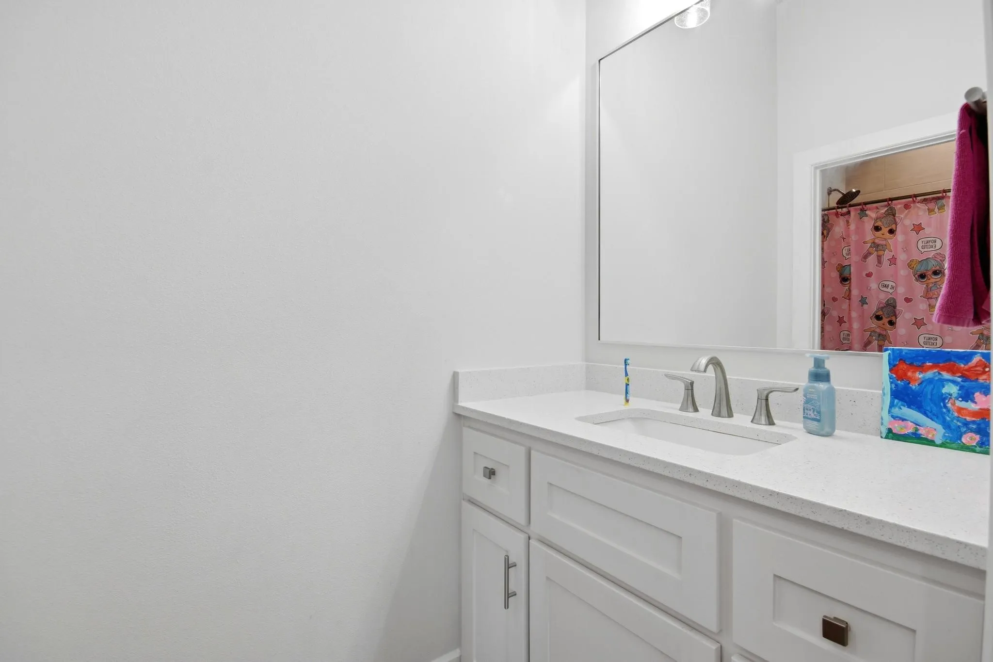 Bathroom vanity featuring a light-colored countertop, an undermount sink, and a brushed nickel faucet