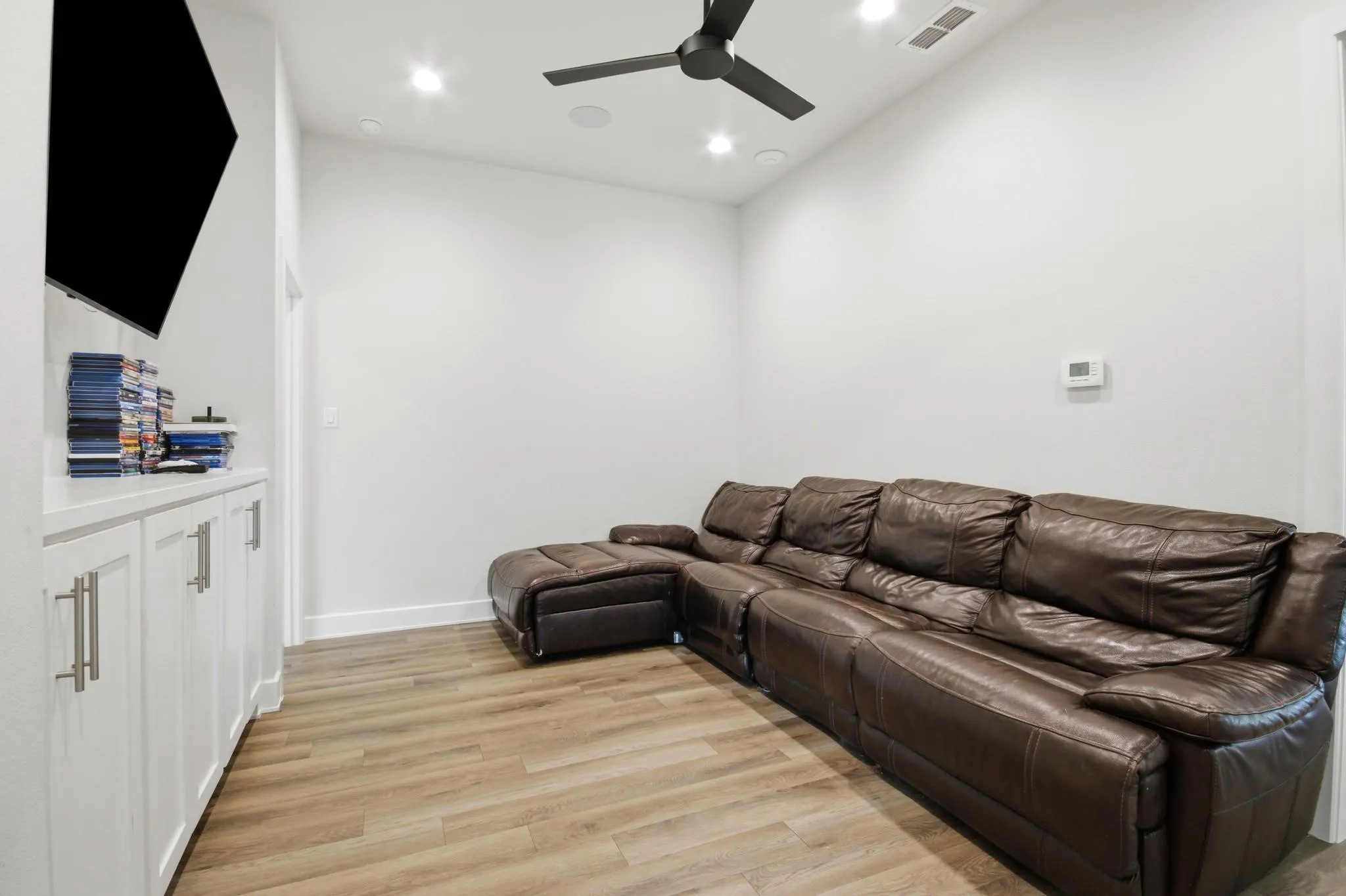 Media room featuring wood-finish flooring and integrated recessed lighting