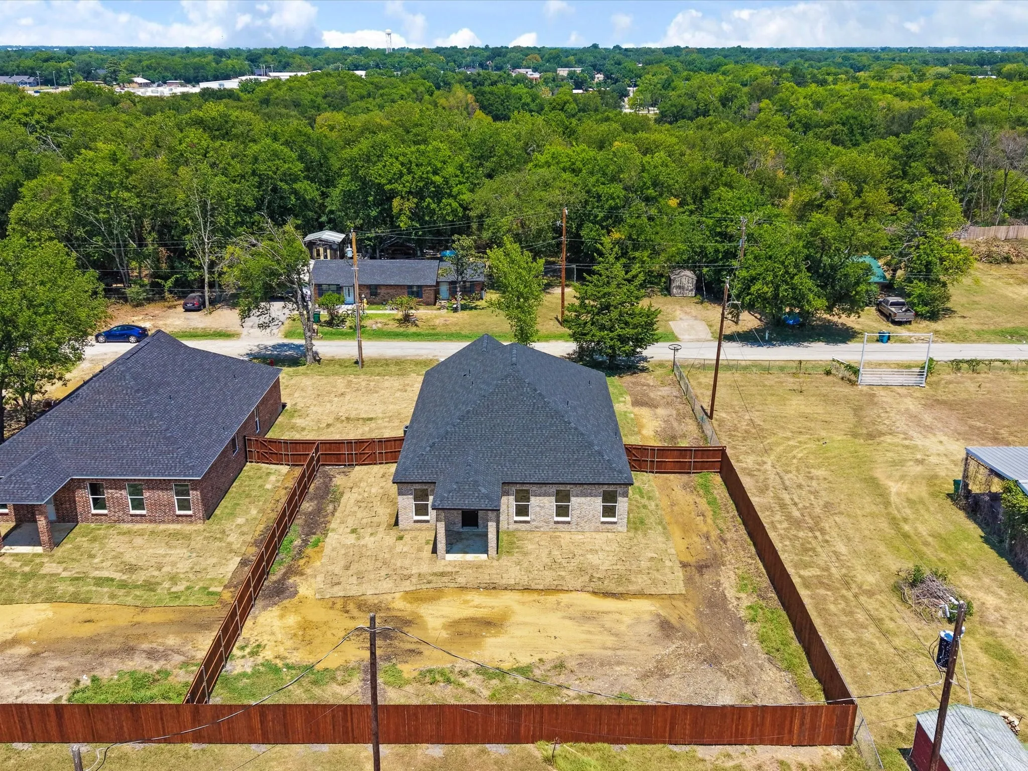 Brick exterior with a dark shingle roof, surrounded by a wood privacy fence