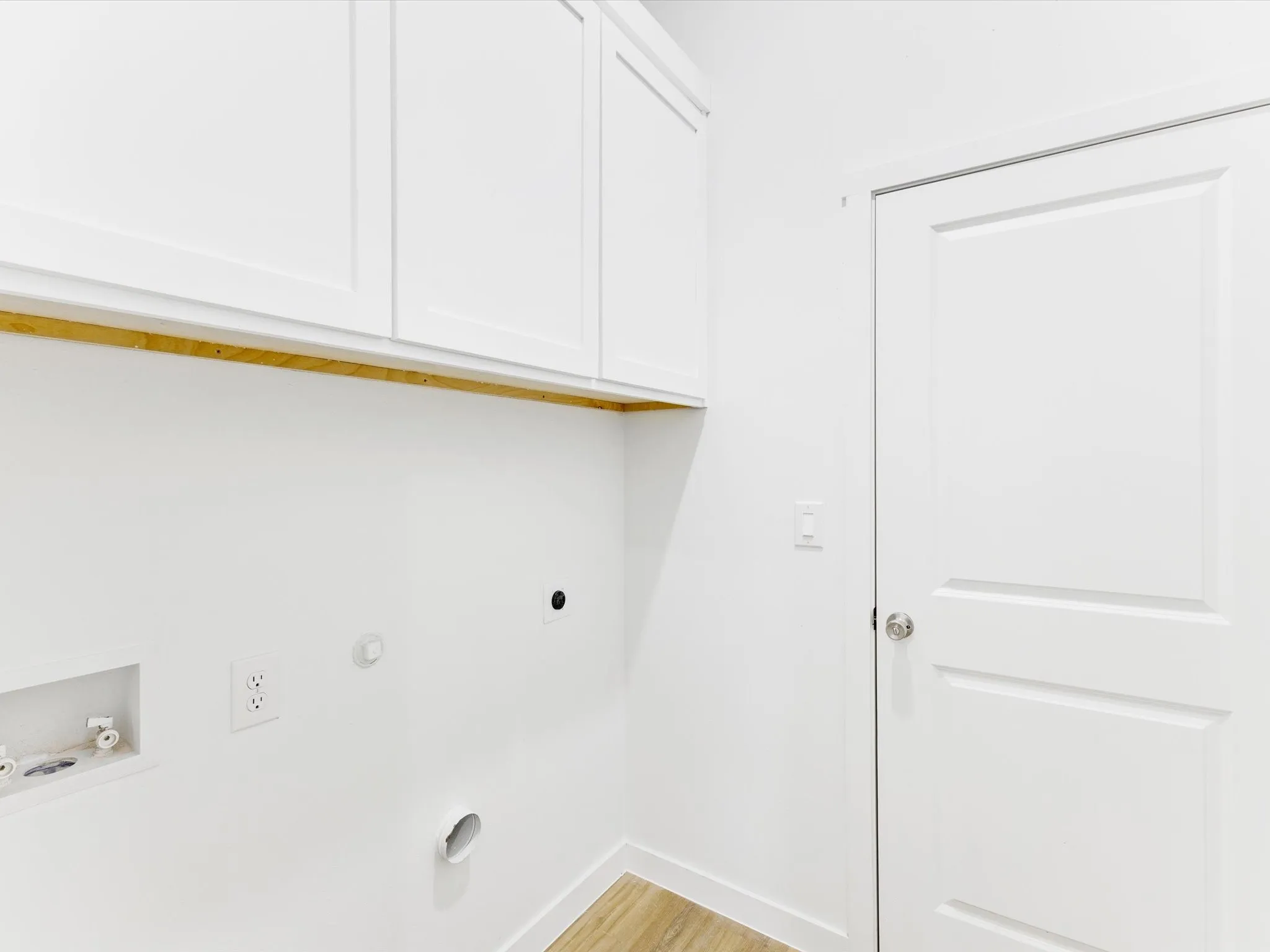 White shaker-style cabinetry, wood-finish flooring, and crisp white walls