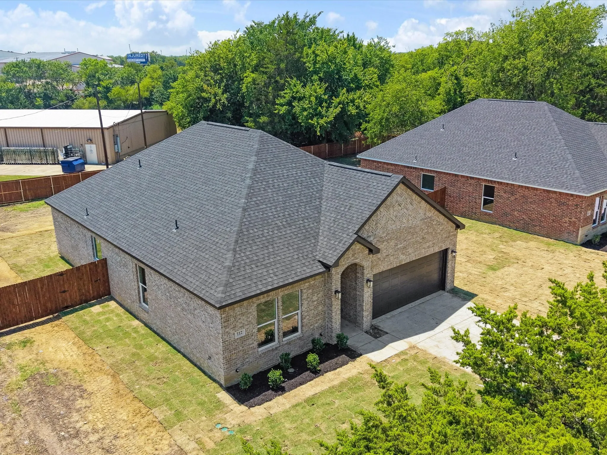 Brick exterior with an attached garage, paved driveway, and established landscaping