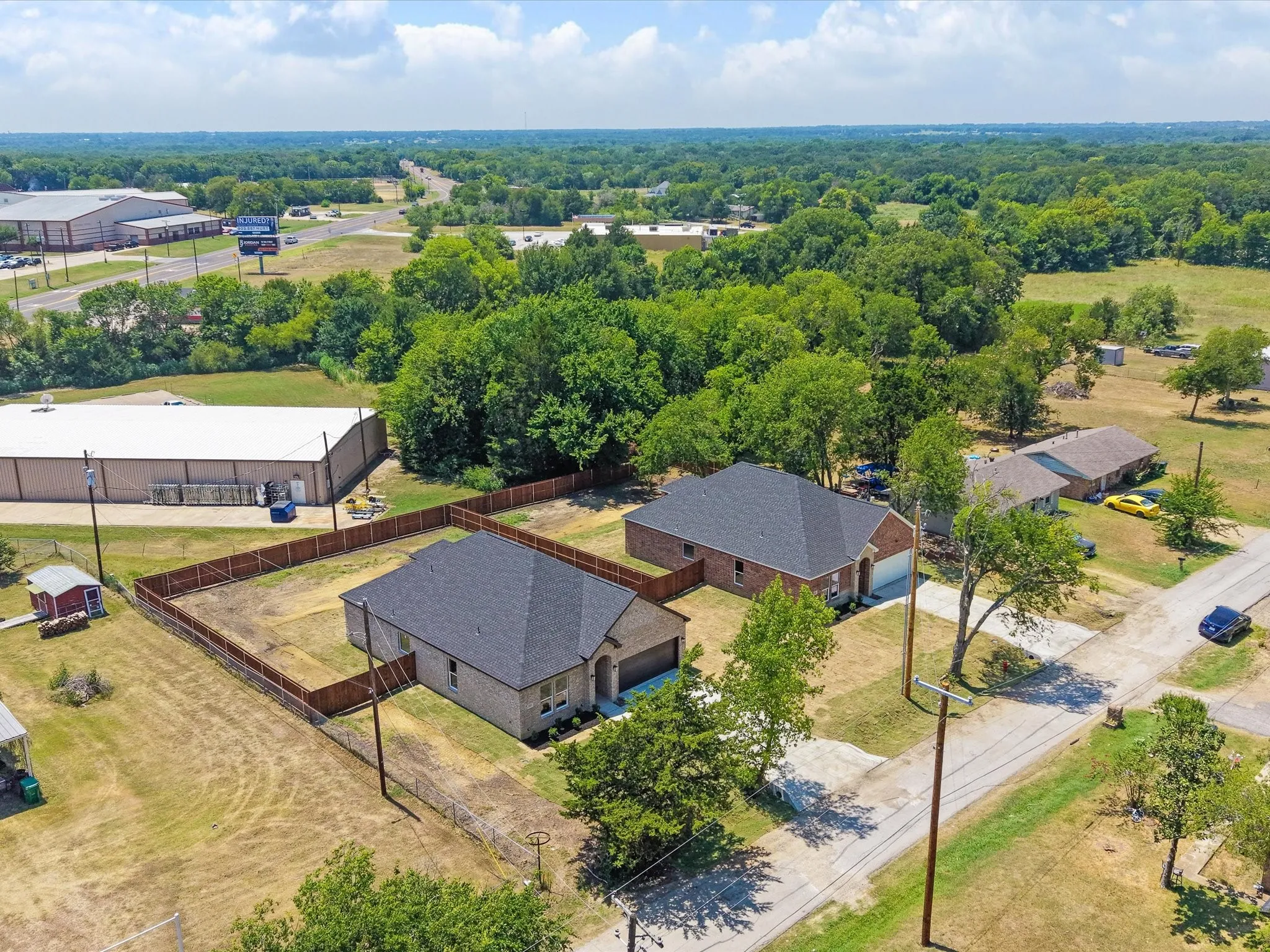 Brick exterior, dark shingle roof, attached garage, fenced yard, and paved driveway